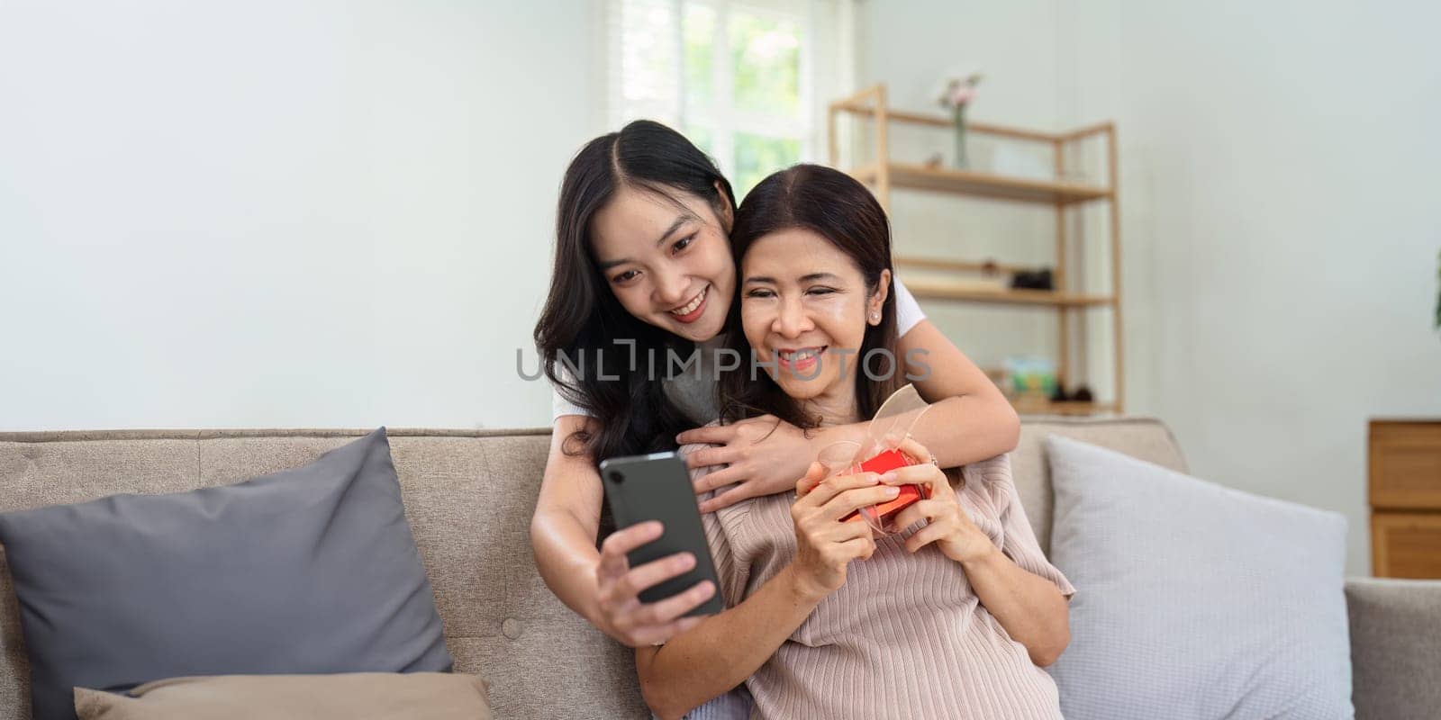 Congratulations. Loving asian mature daughter surprised mother with present in Mother's Day, giving her handmade card and gift box.