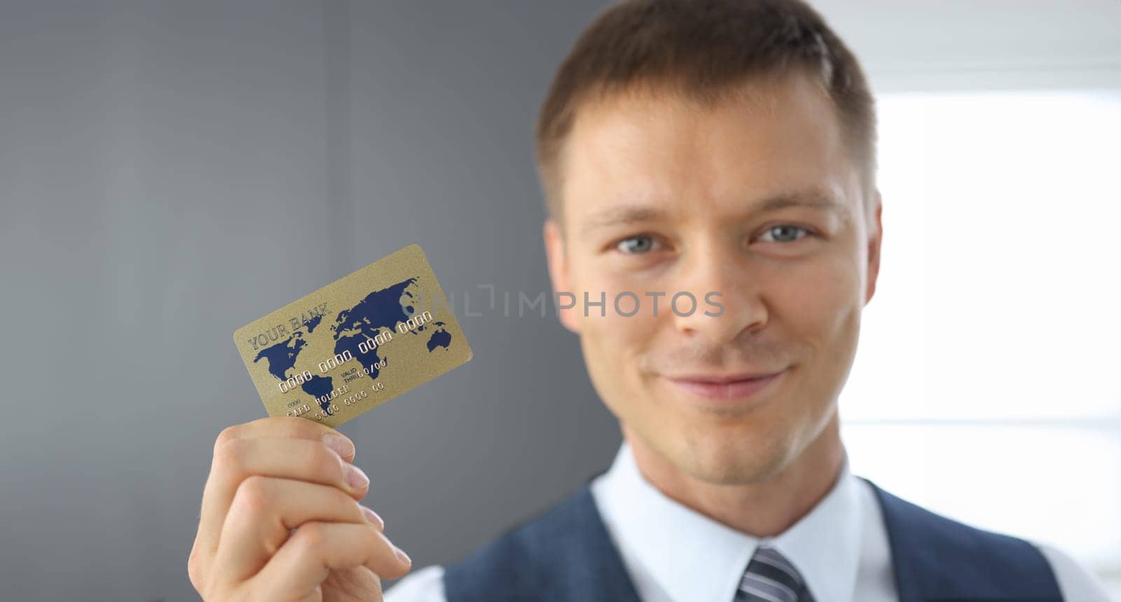 Gold bank card with letters and numbers close-up. Happy man hold plastic card in hand.