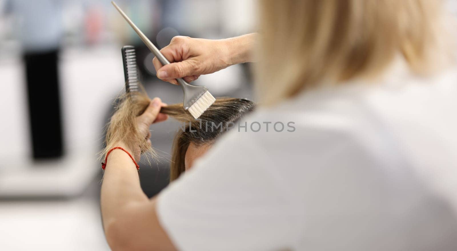 Hair dye with brush close-up. Woman hold lock of client hair and makeover.