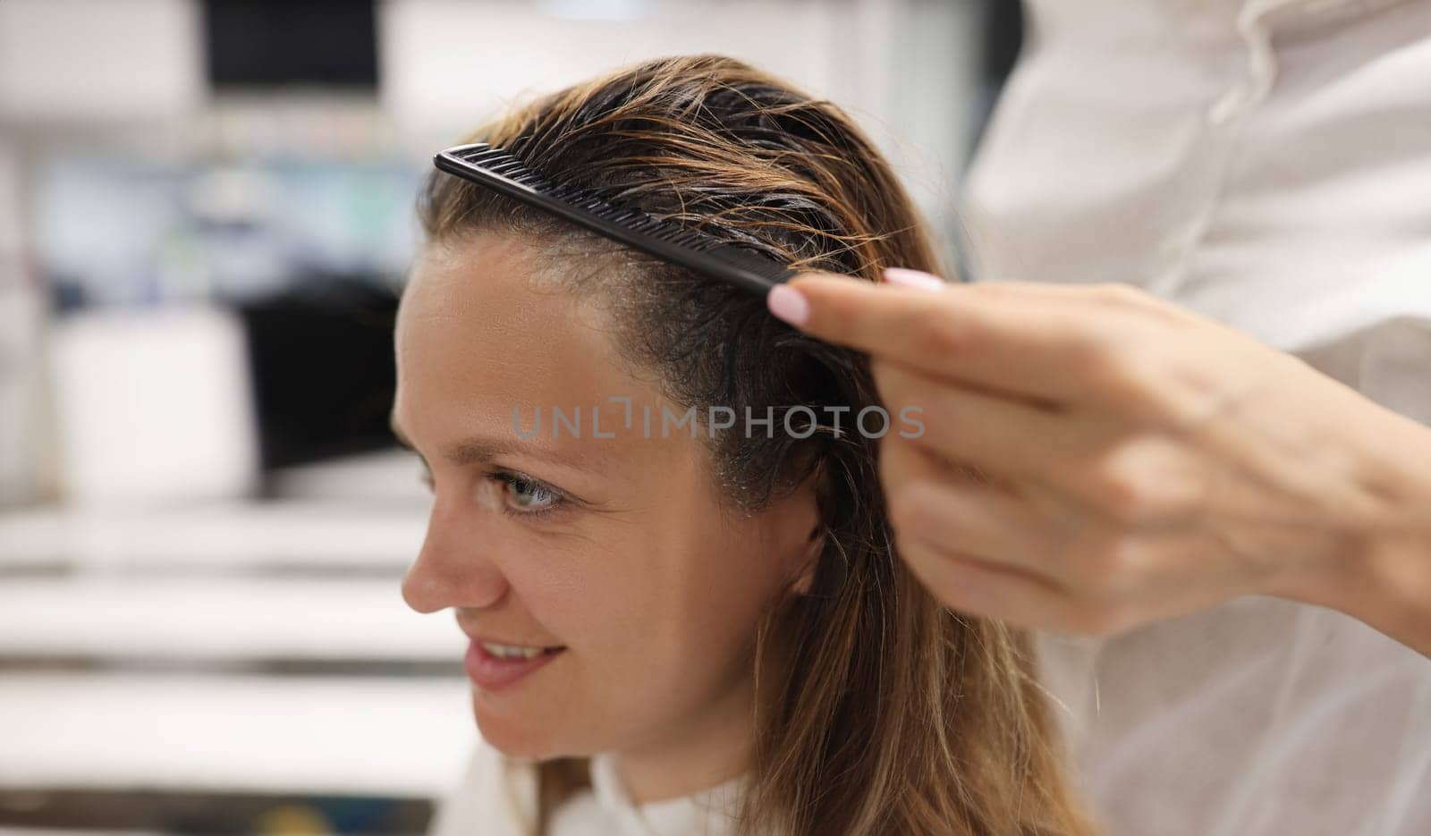 Portrait of woman close-up side view. Hairdresser comb dyed hair in beauty salon.