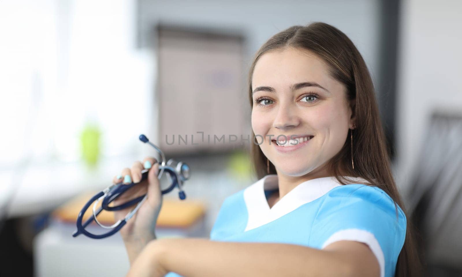 Close-up of cheerful therapist looking at camera with happiness and smile. Beautiful practitioner holding stethoscope. Healthcare and medicine concept