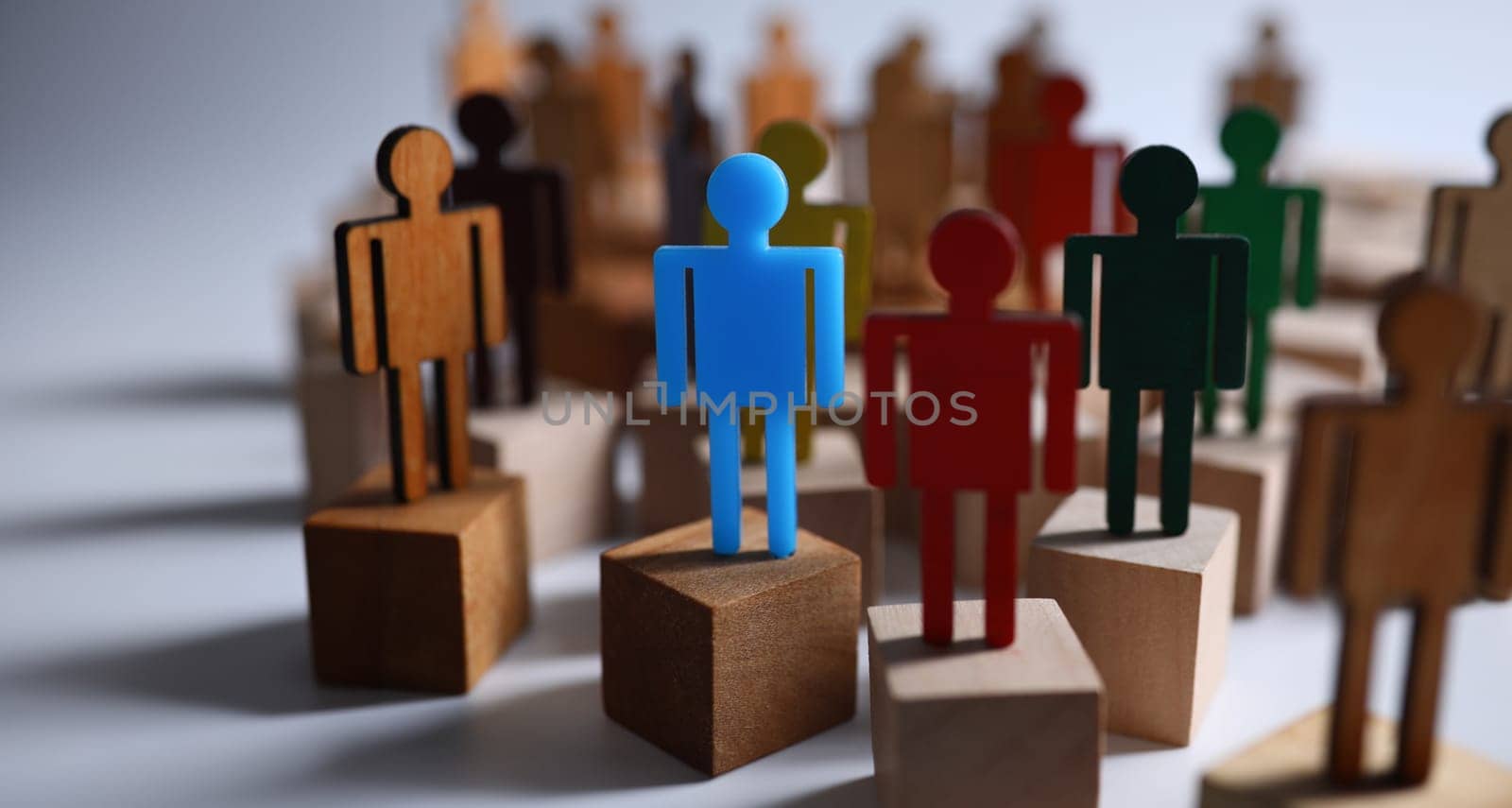 Close-up of colourful plastic figures standing on wooden blocks. Symbol of leadership and uniqueness. Business and success in career. Strategy and goal planning concept