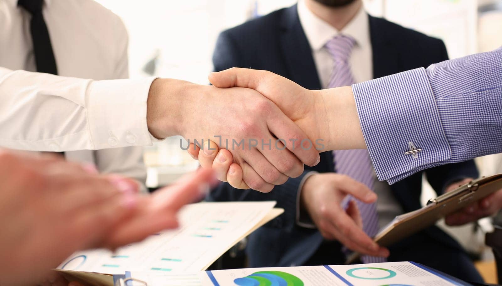 Group of businessmen shaking hands after productive meeting closeup