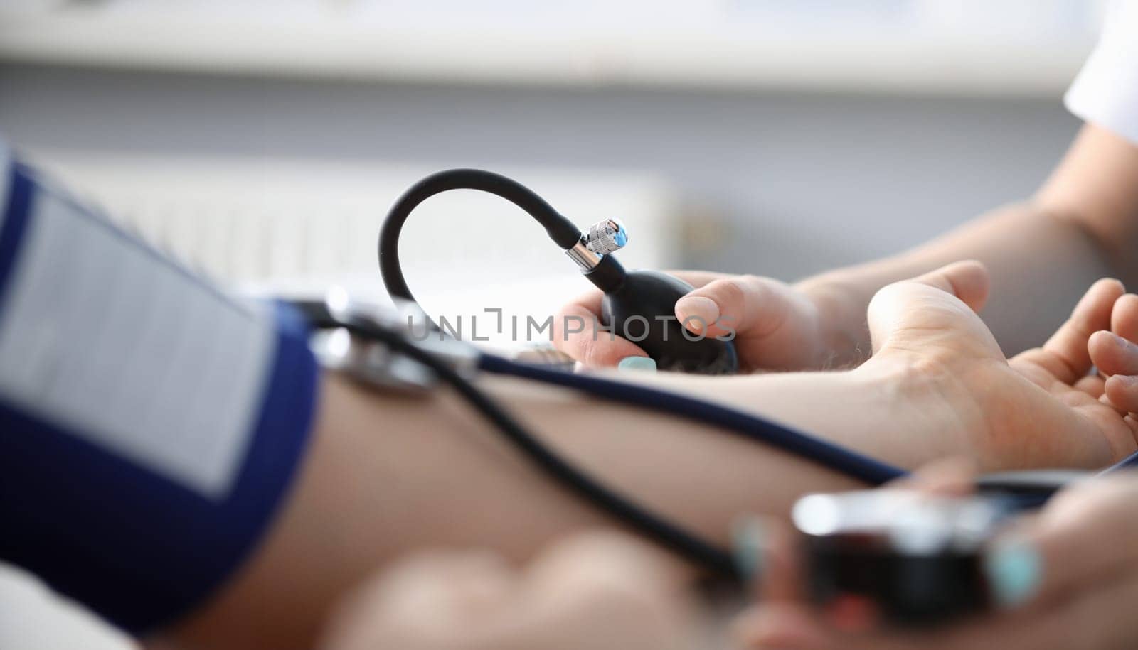 Close-up of persons hand on desk and doctor measuring blood pressure. Planned diagnostic. Modern equipment to examine circulation. Medicine and appointment concept