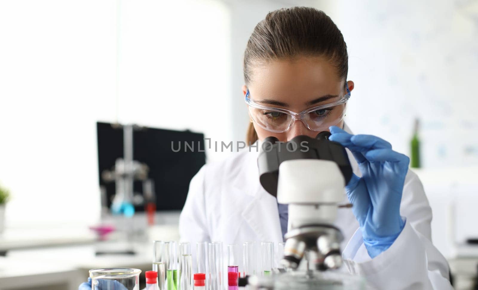 Close-up of scientist using microscope and test tubes. Laboratory assistant making analysing sample of medicines in research lab. Chemical experiments concept