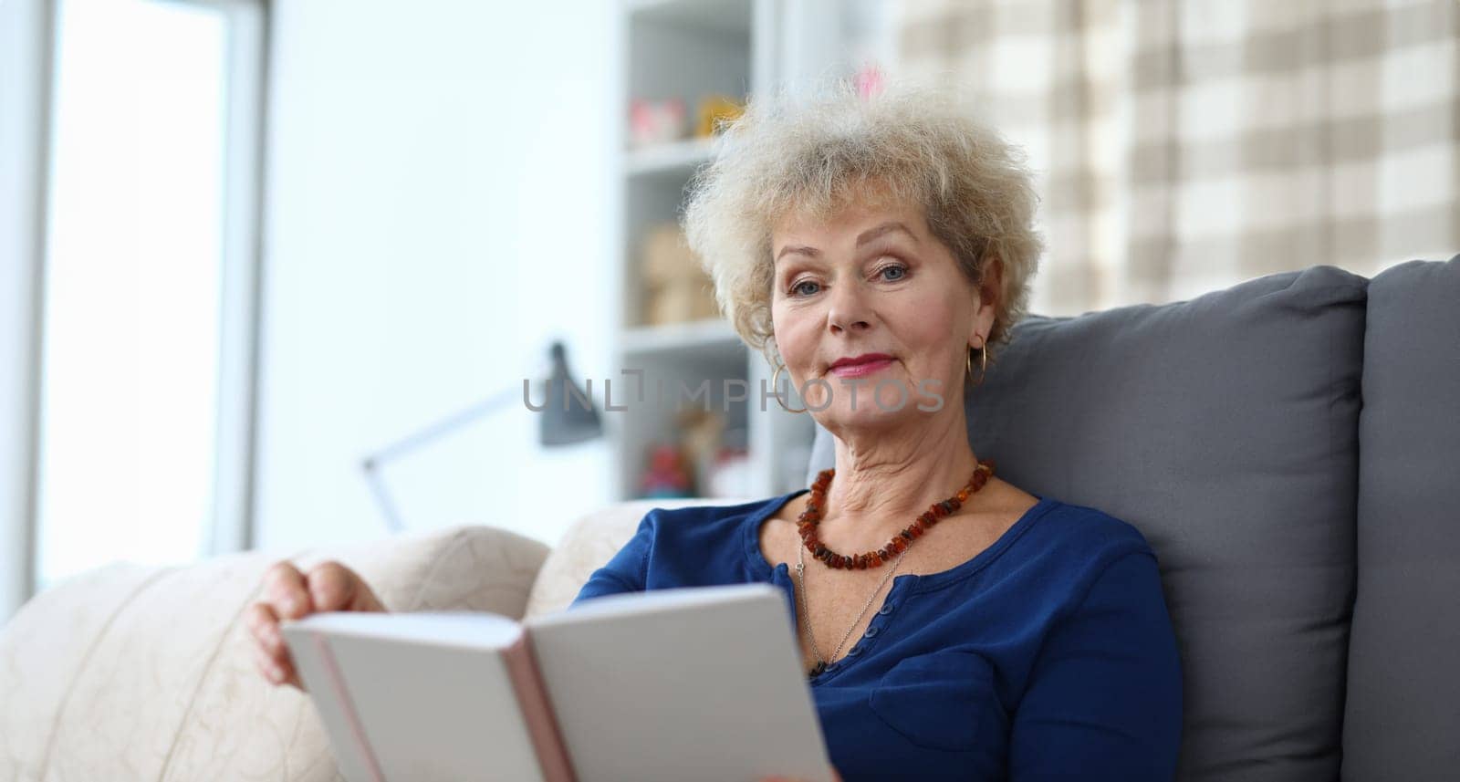 Elderly woman self-isolation reading book at home by kuprevich