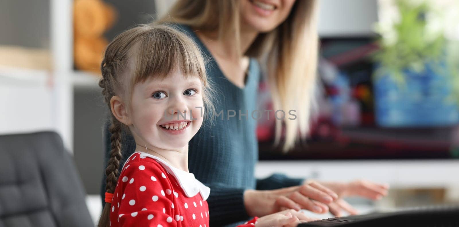 Mom teaches daughter to play electronic piano by kuprevich
