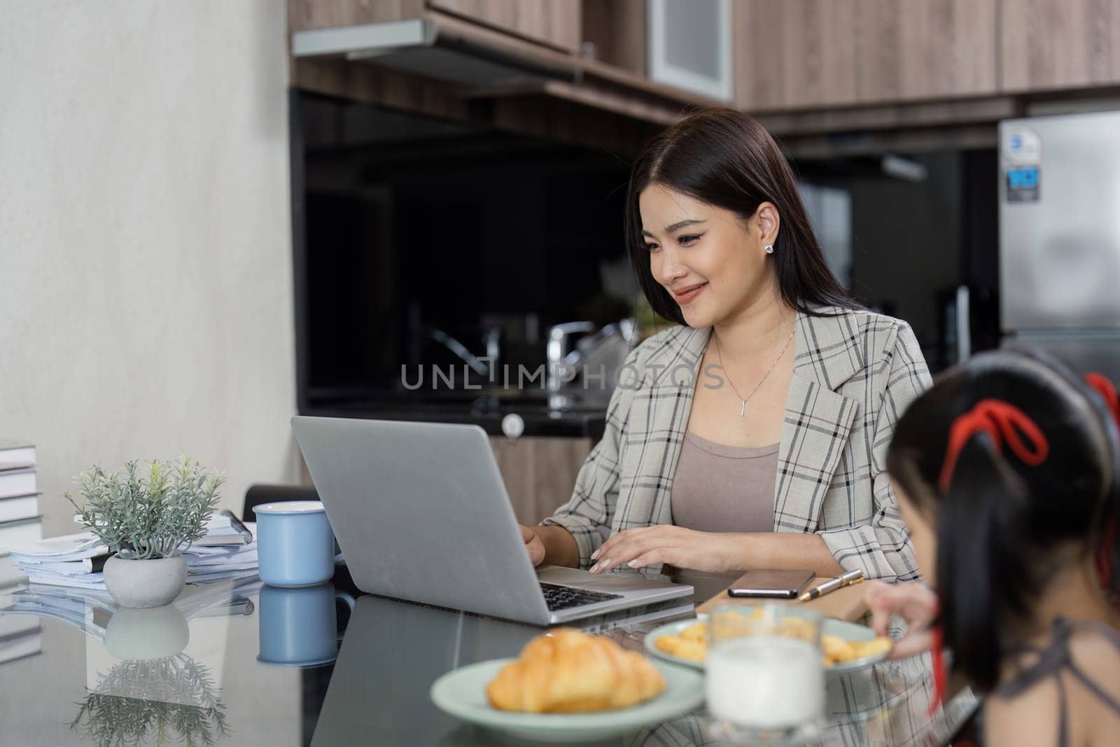 Business woman working at home. working woman working on laptop and take care of her daughter during summer by itchaznong