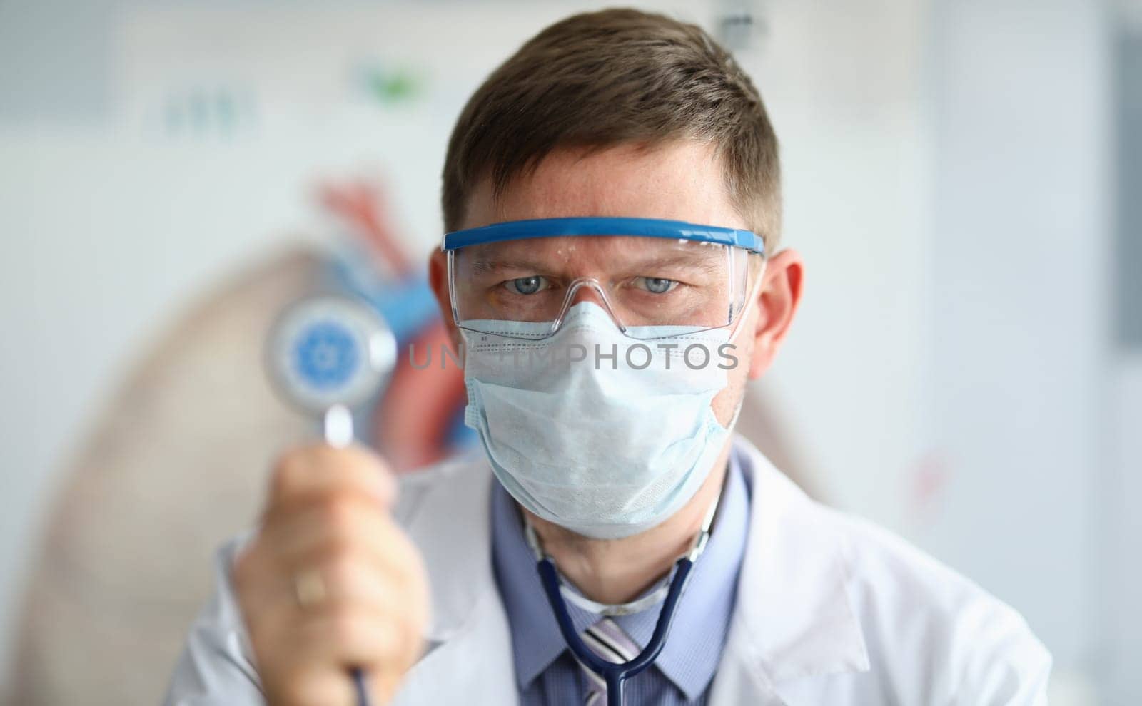 Male doctor hold in hand stethoscope with coronavirus symbol closeup. by kuprevich