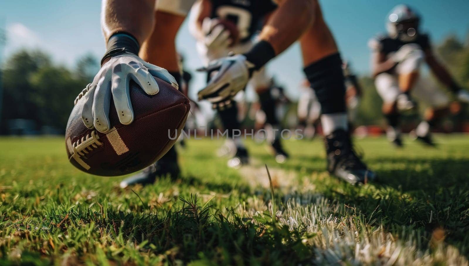 Low-angle close up view of a football player hiking a football during a football game. Focus on the ball and hands.