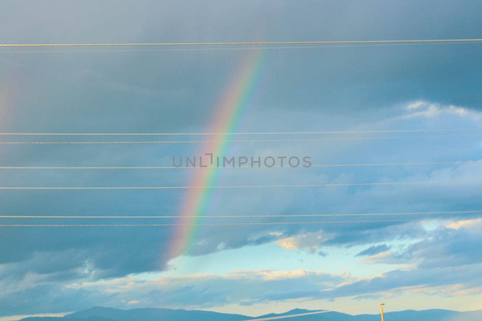 Embark on a visual journey as you capture the stunning beauty of a rainbow set against a backdrop of dramatic clouds