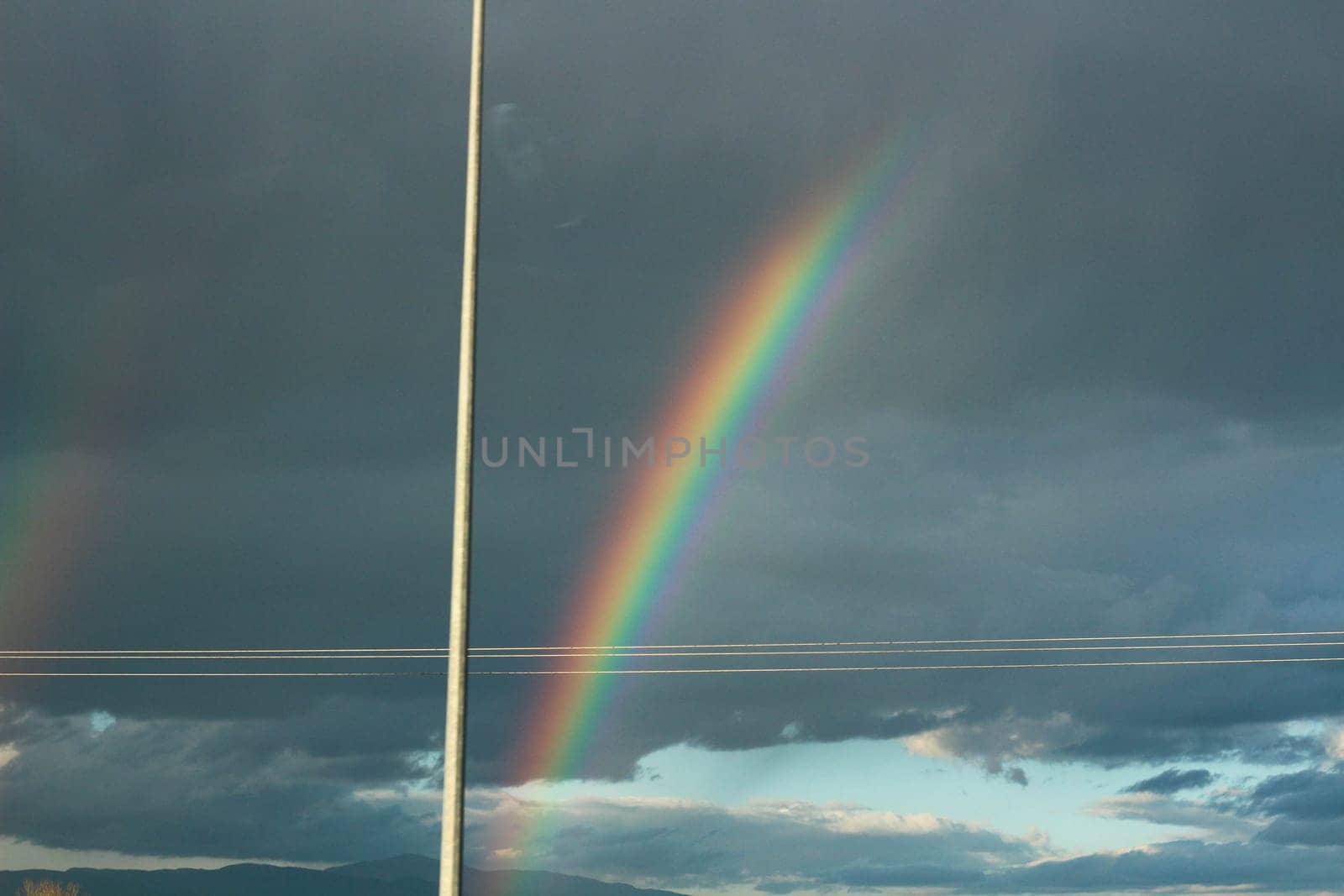 Embark on a visual journey as you capture the stunning beauty of a rainbow set against a backdrop of dramatic clouds