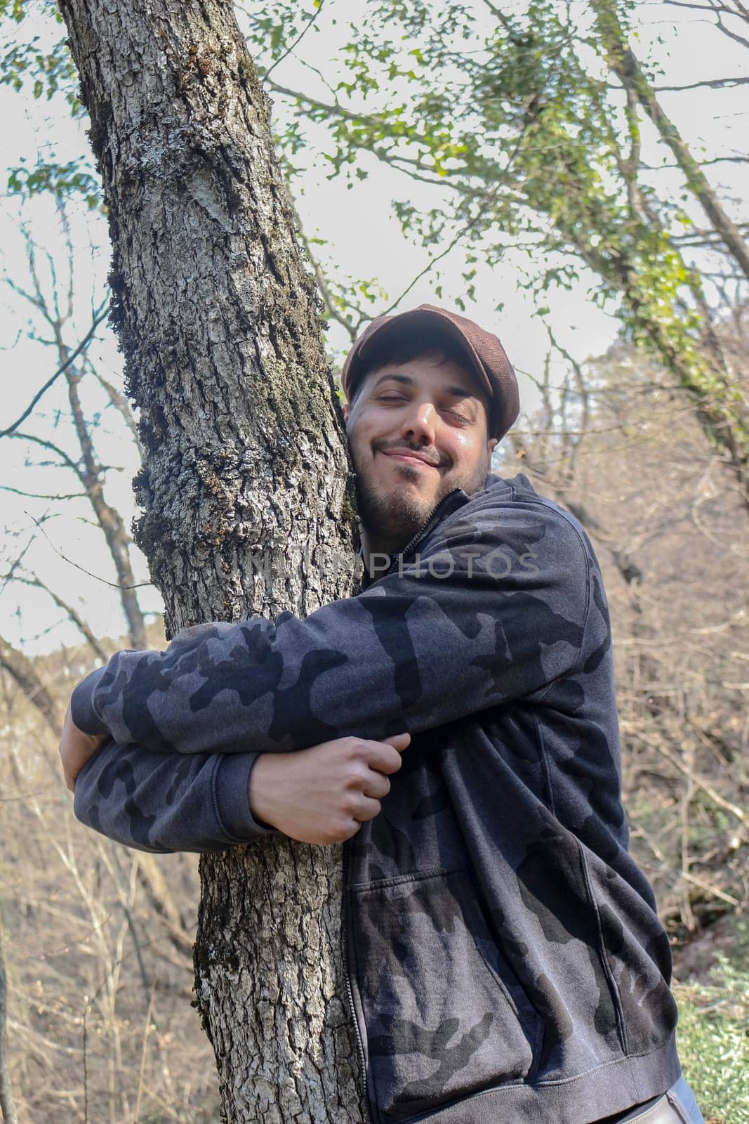 Witness the poignant moment as a young man envelops a majestic tree in a warm embrace