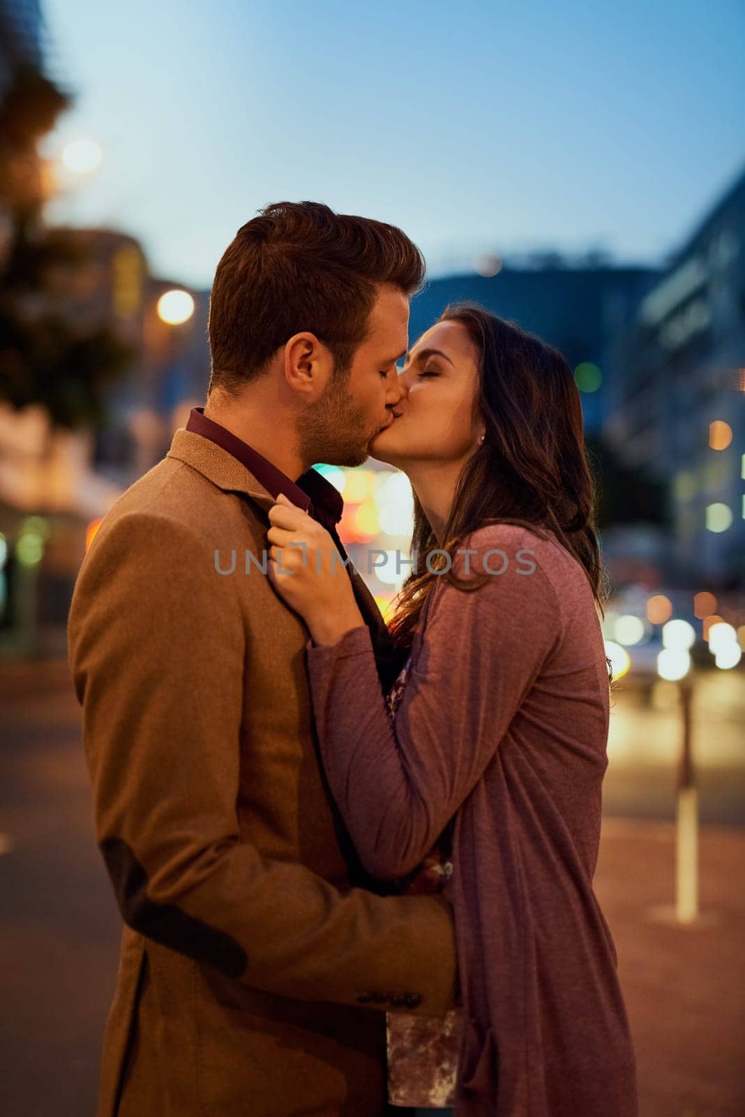 Couple, night and city with kiss on date, romance and bonding with love in relationship. Happiness, affection and people with commitment and trust, sweet moment and romantic together outdoor by YuriArcurs