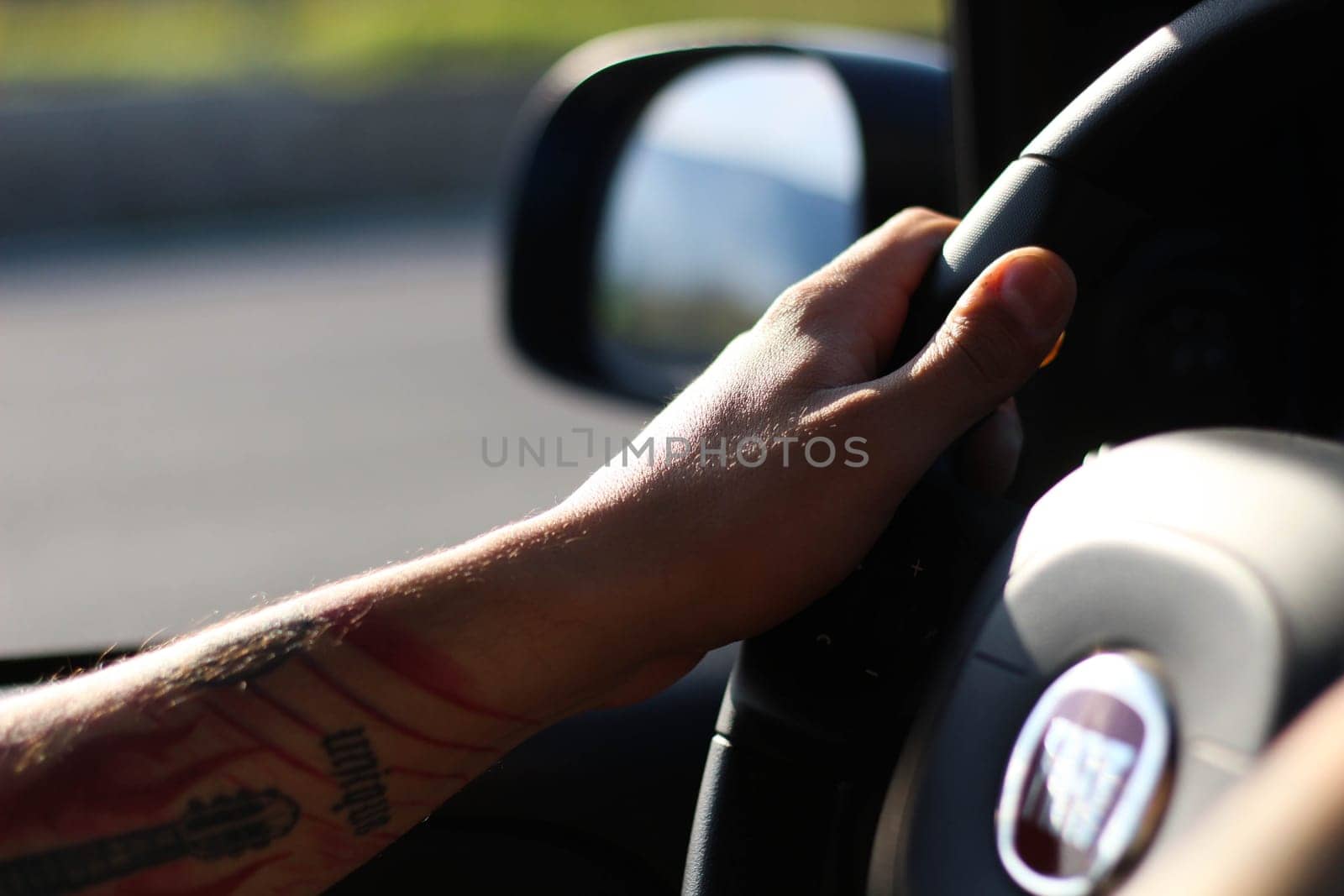 Inked Journey: Tattooed Arm Commanding the Wheel by DakotaBOldeman