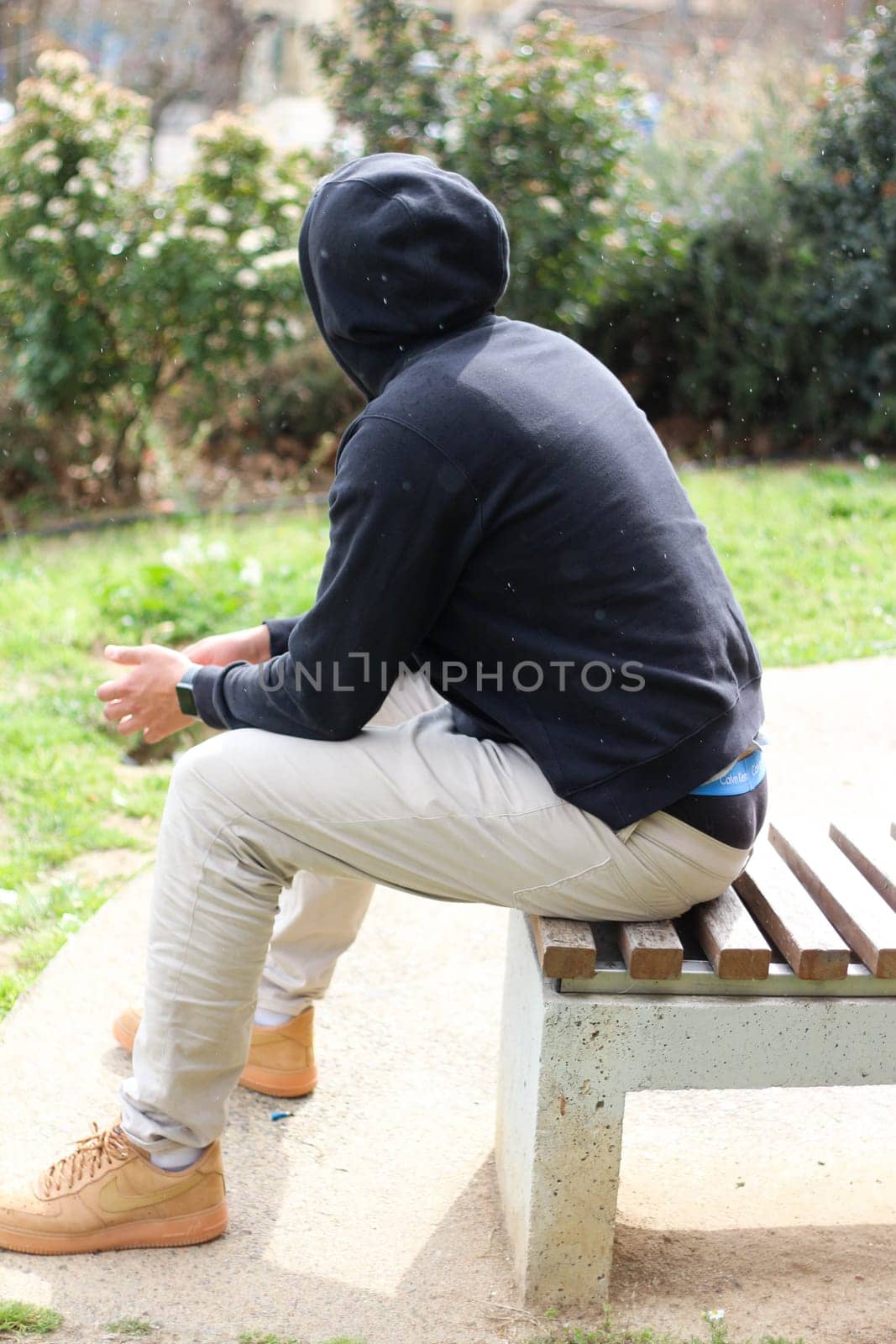 Enter the tranquil moment where a young man sits on a bench, enveloped in solitude and contemplation. With a serene demeanor, he gazes into the distance, lost in thought