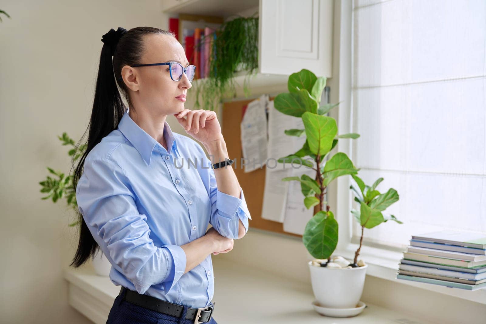 Serious thoughtful woman in her 30s looking out the window by VH-studio