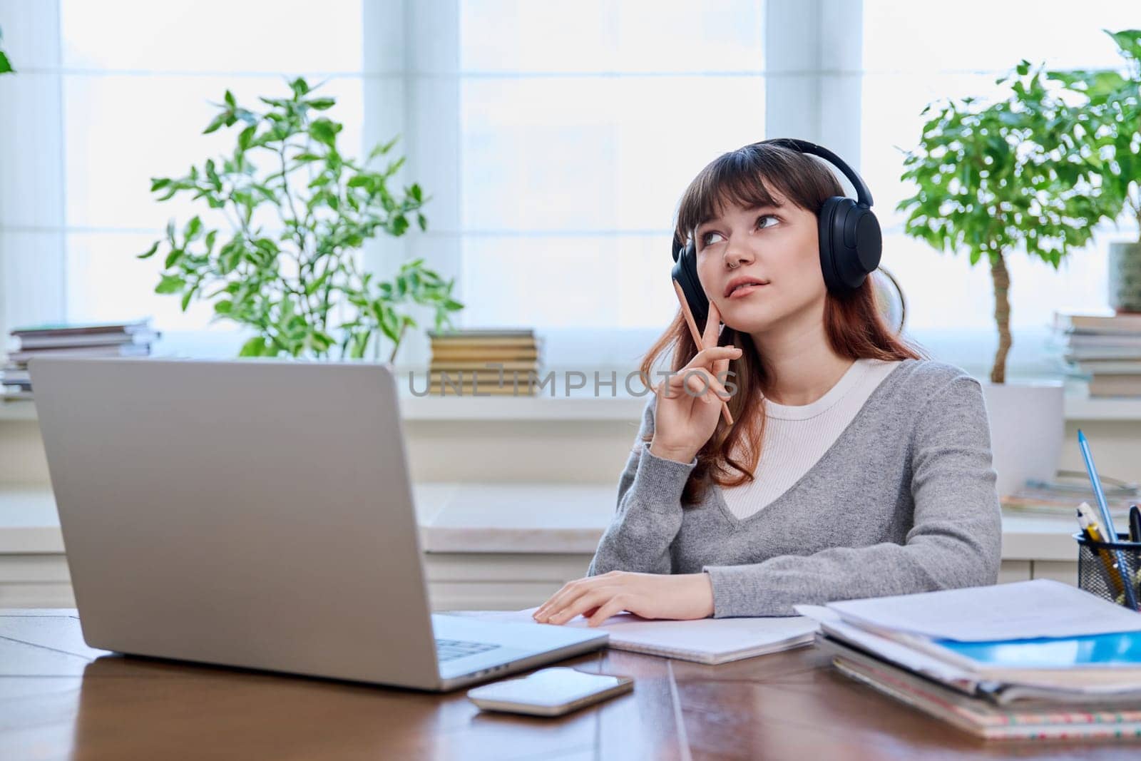 Girl teenage student in headphones having video chat online on computer by VH-studio