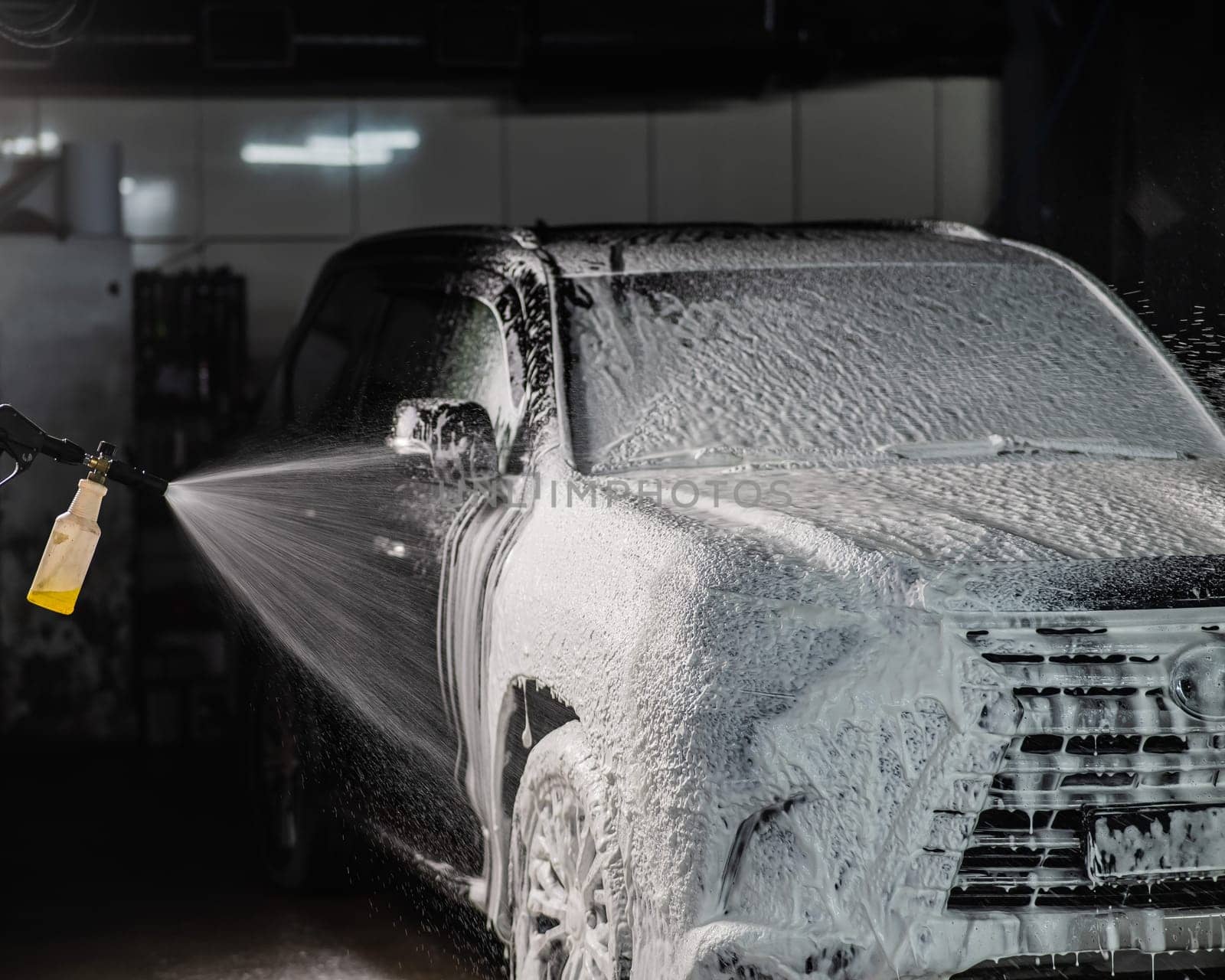 Man applying foam to black car in car wash. by mrwed54