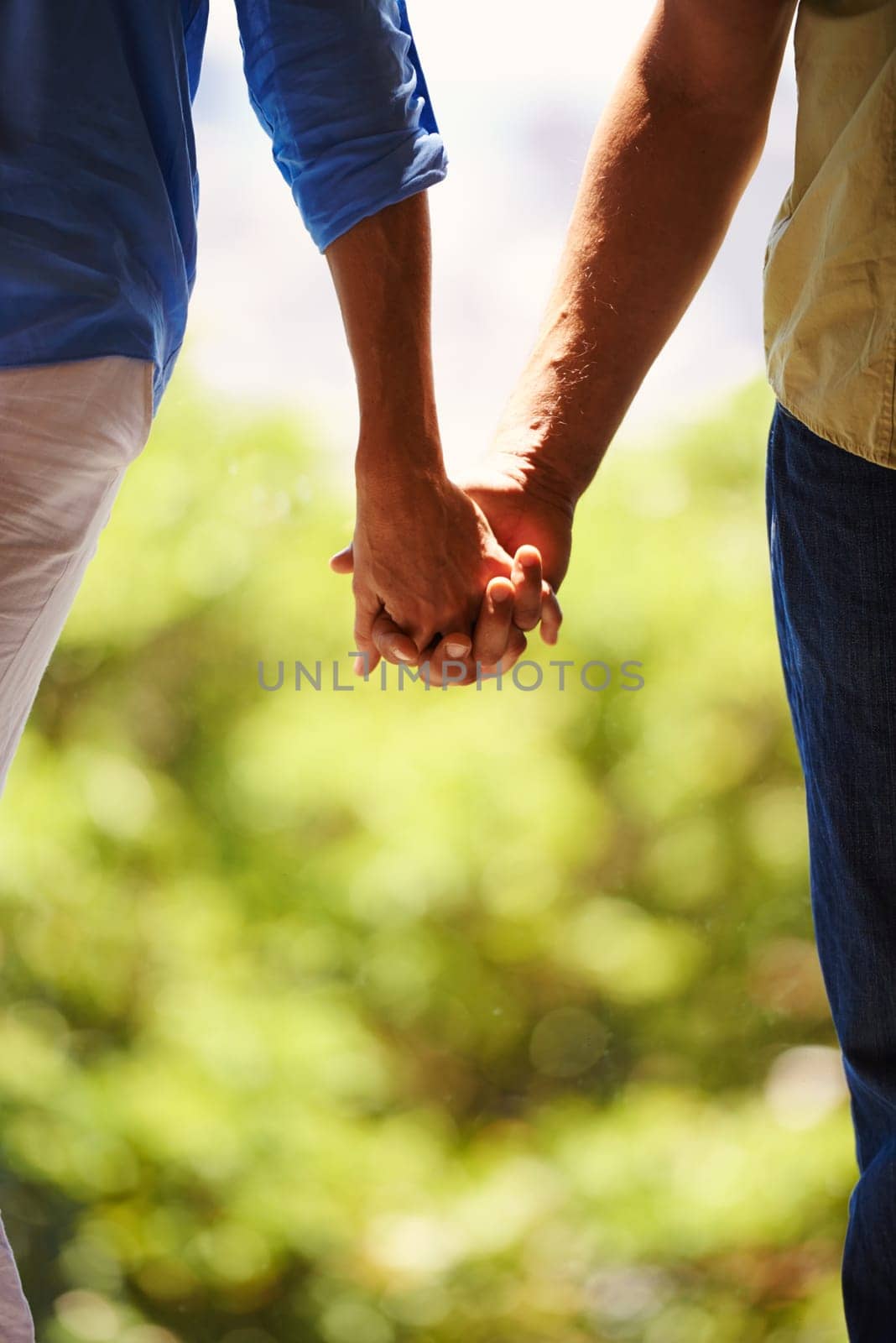 Couple, holding hands and bonding together outdoor for romance and commitment in healthy relationship. People, love and holiday with touch for care, security and walking for date in countryside by YuriArcurs