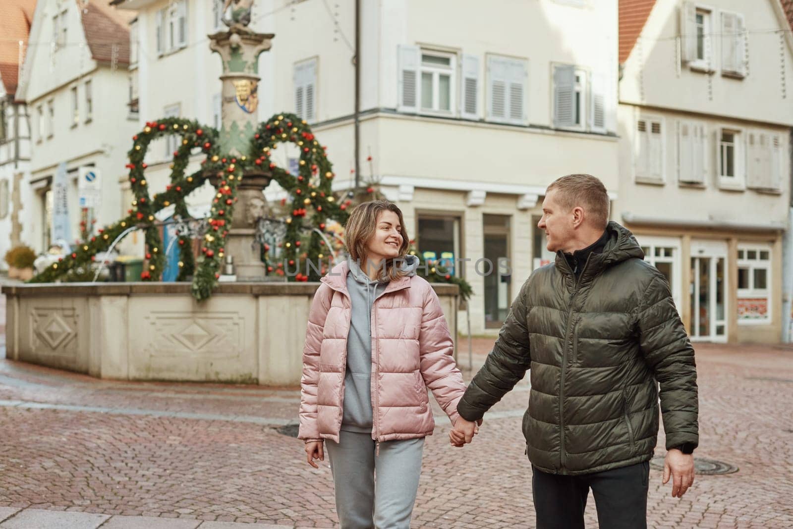 Loving couple of tourists walking around old town. Man woman couple walking europe old town Germany. Couple of lovers leisurely stroll in the cool autumn morning on the streets of a BIETIGHEIM-BISSINGEN (Germany). The guy holds his wife. Vacation, autumn, holiday. Couple Walking in Europe's Old Town