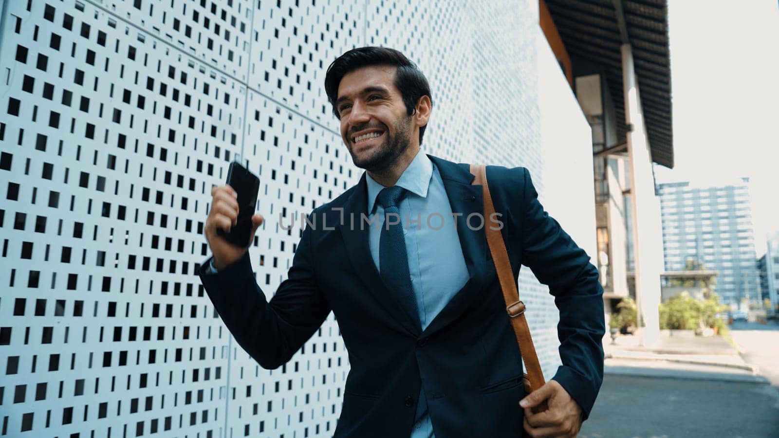 Happy smart business man celebrate for getting promotion or receive good news while walking at street. Skilled project manager or leader express feeling of overjoy at architectural building. Exultant