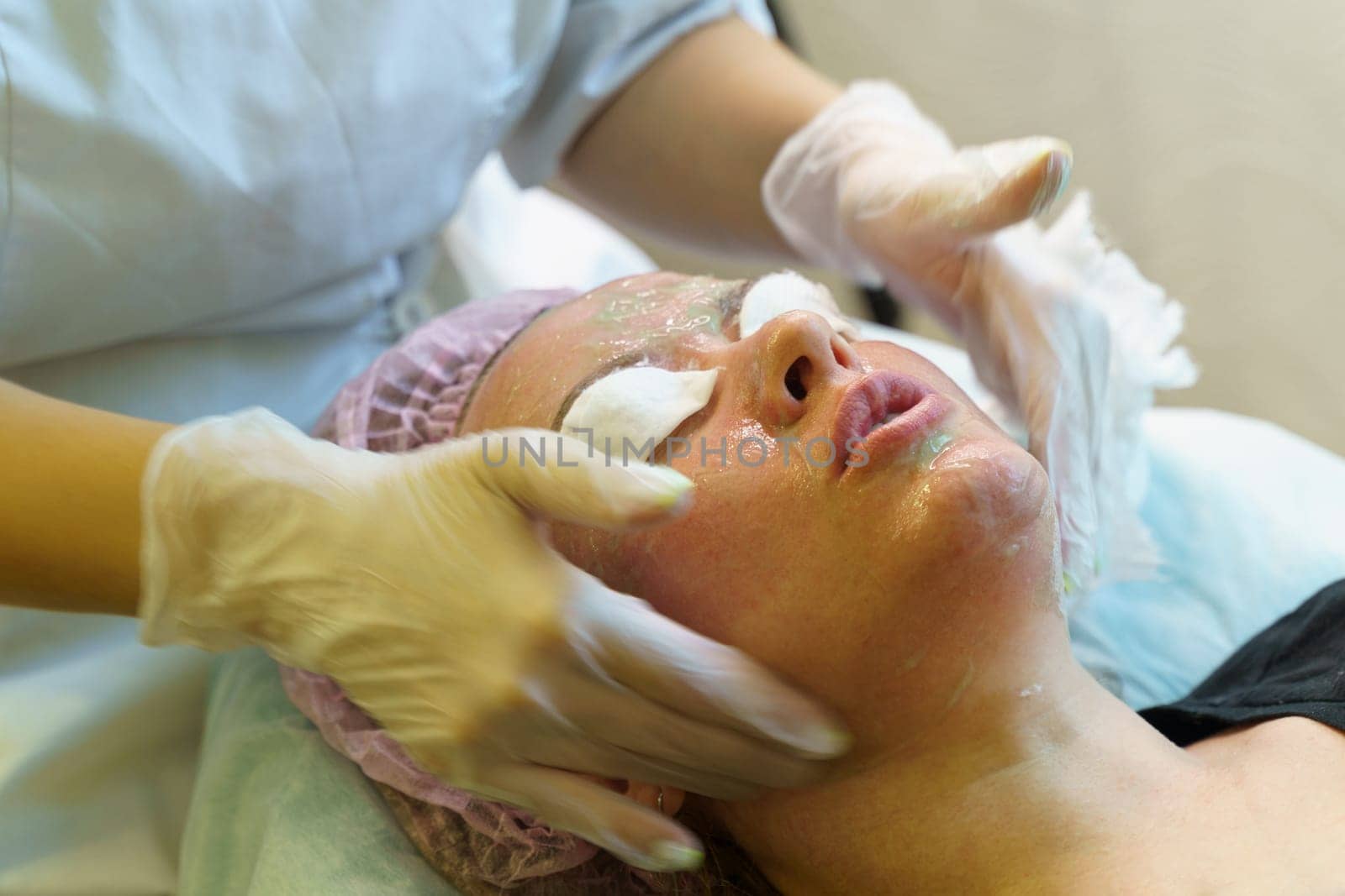 A woman getting a facial mask applied to her face at a spa or skincare clinic.