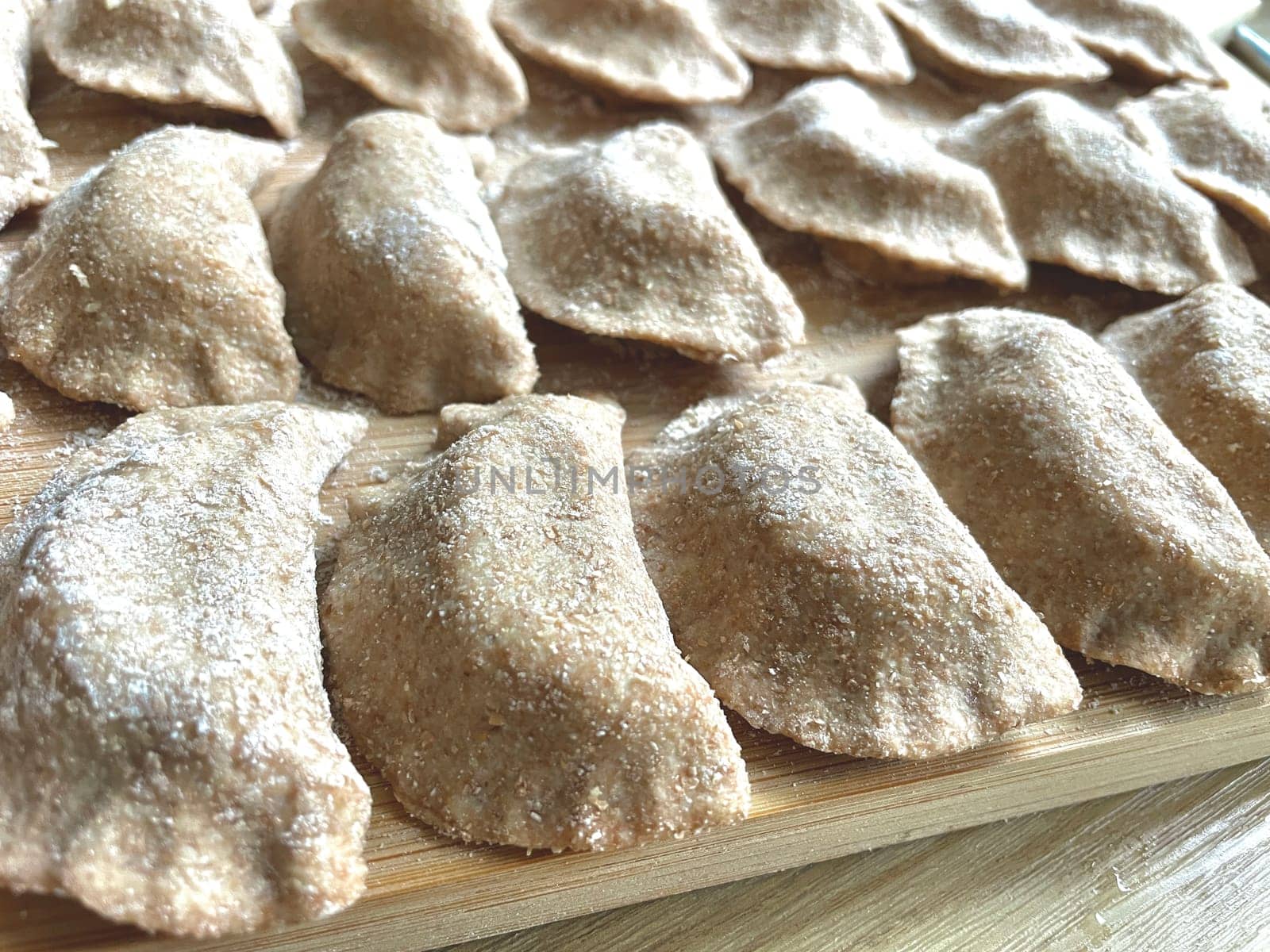 Dumplings made of whole wheat flour are molded on the kitchen board. High quality photo