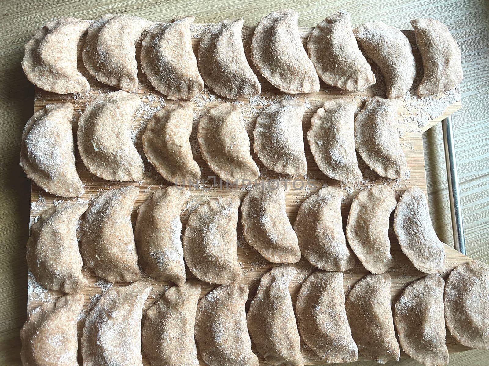 Dumplings made of whole wheat flour are molded on the kitchen board. High quality photo