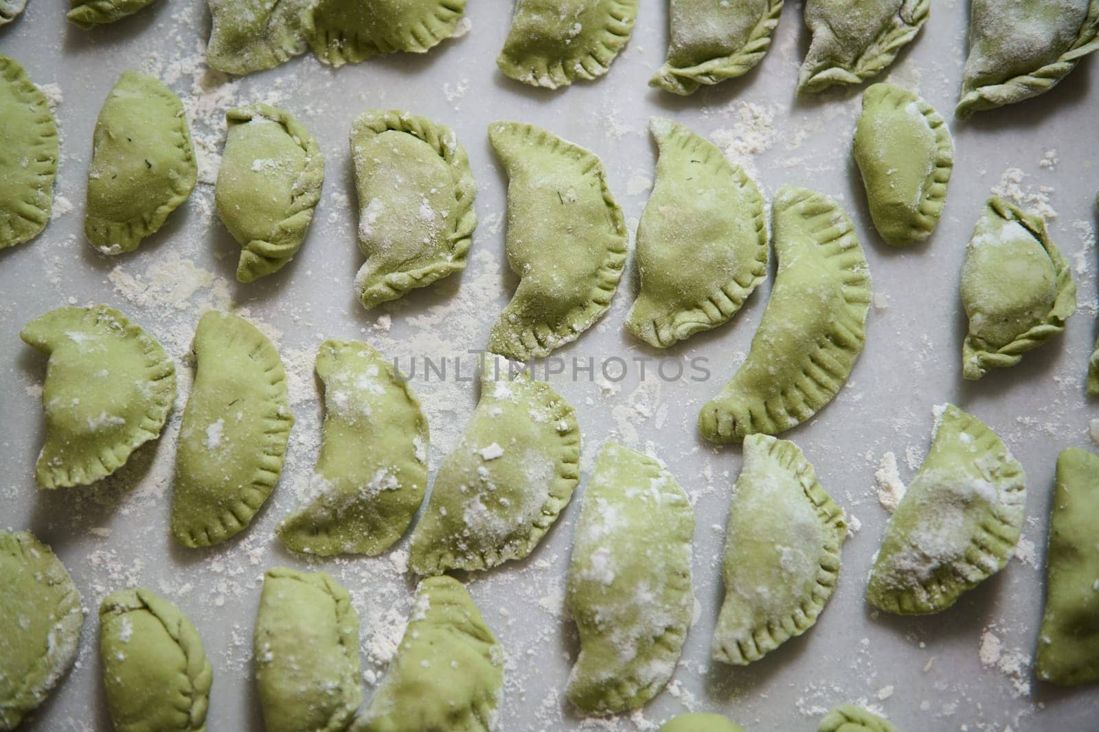 Top view.Varennyky and ravioli on a floured marble surface of kitchen table. Food background with molded raw dumplings. Ukrainian traditional cuisine. Food. Traditions and culture by artgf