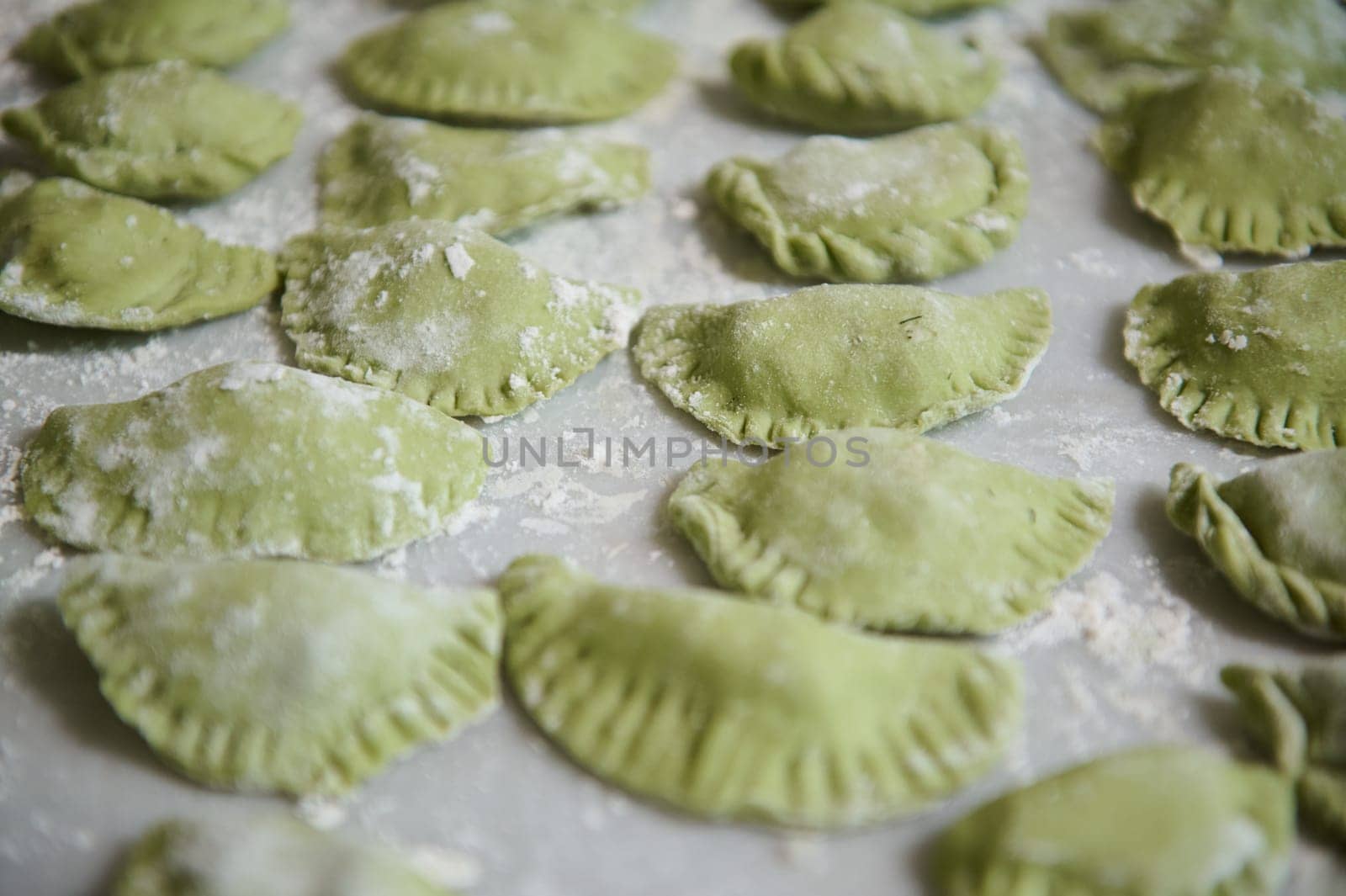 Food background with molded raw dumplings. Varennyky and ravioli on a floured marble surface of kitchen table. Ukrainian traditional cuisine. Food. Traditions and culture by artgf