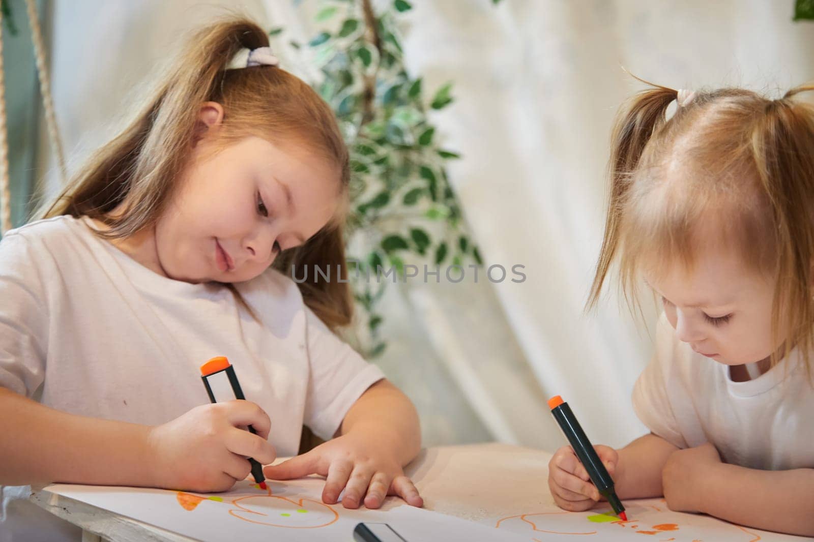 Cute little sisters are painting on table. Preschooler, 4 and 8 years child in living room. Small girl kids doing homework, home schooling concept