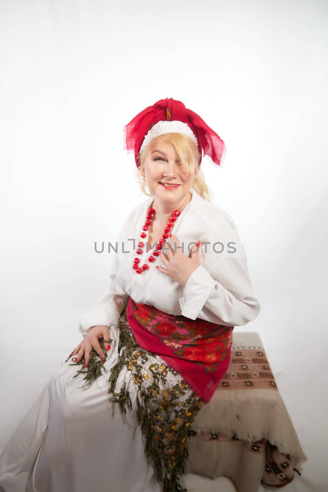 Portrait of a cheerful funny adult mature woman solokha. Female model in clothes of national ethnic Slavic style. A stylized Ukrainian, Belarusian or Russian woman poses in a comic photo shoot by keleny