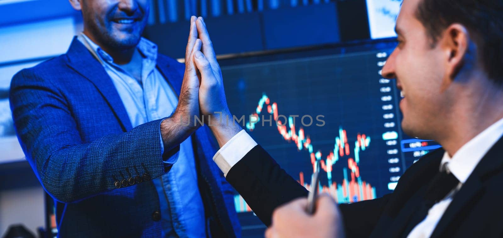 Cheerful two stock exchange traders giving high five for digital currency achievement on dynamic database background. Successful investors earning highest profit analyzed by market graph. Sellable.