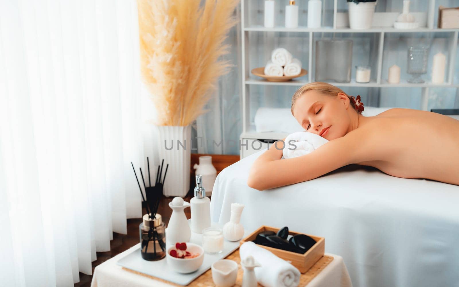 Caucasian woman customer enjoying relaxing anti-stress spa massage and pampering with beauty skin recreation leisure in day light ambient salon spa at luxury resort or hotel. Quiescent