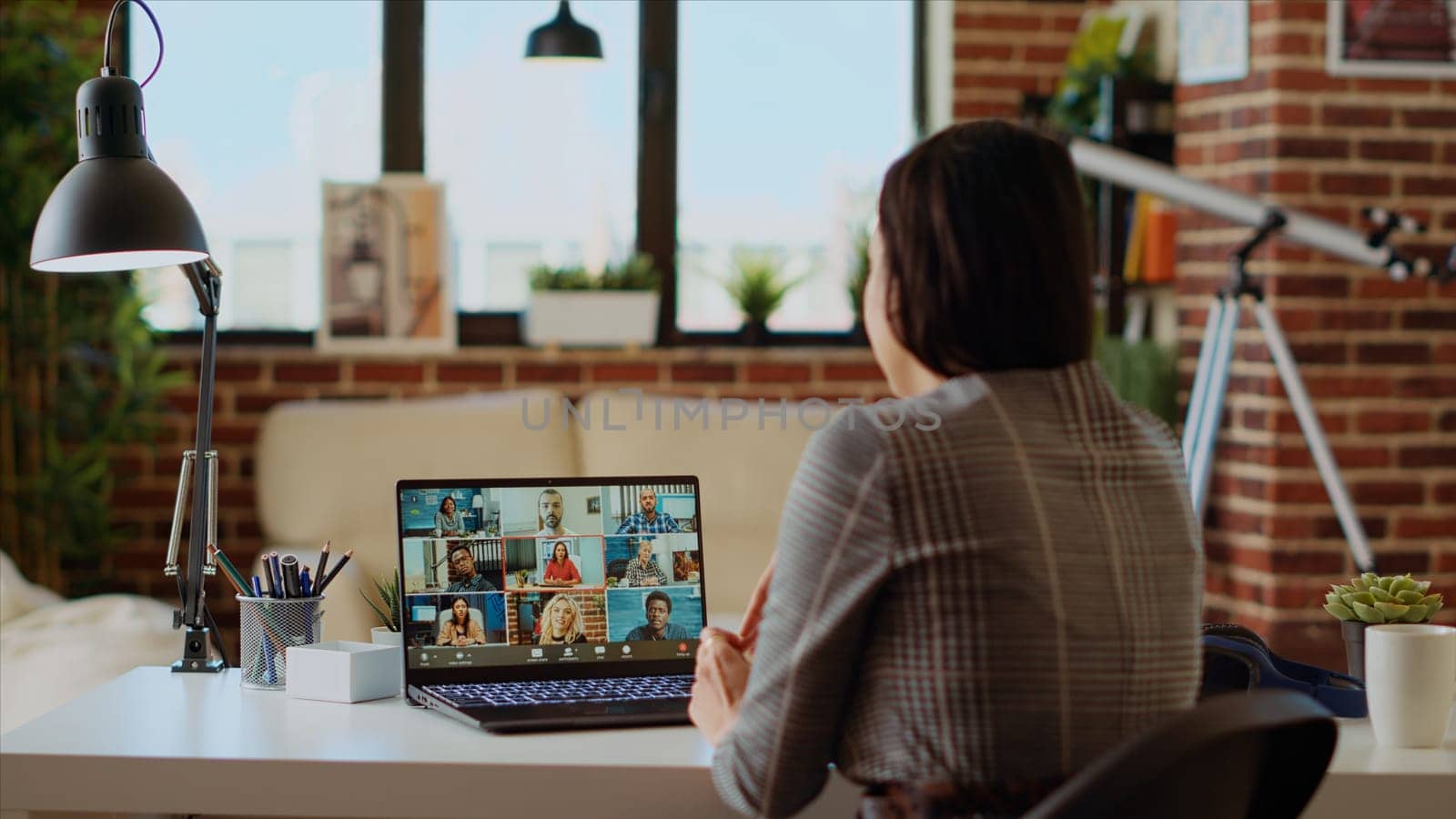 Teleworker at home participating in internet videocall with colleagues, by DCStudio