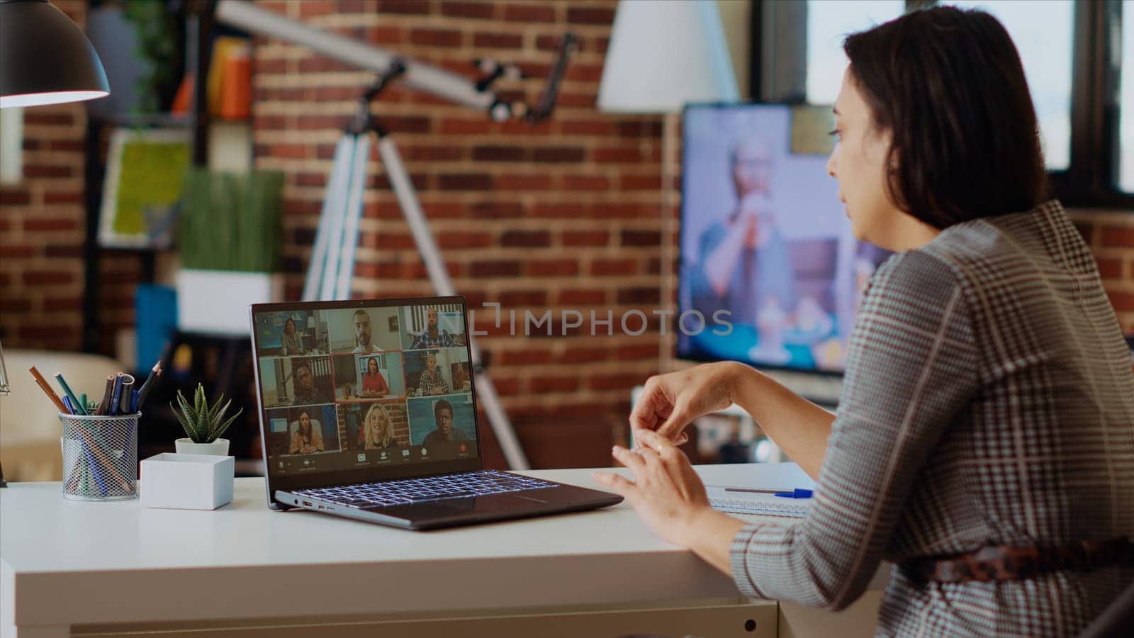 Teleworking team leader in cozy apartment discussing with coworkers in videocall by DCStudio