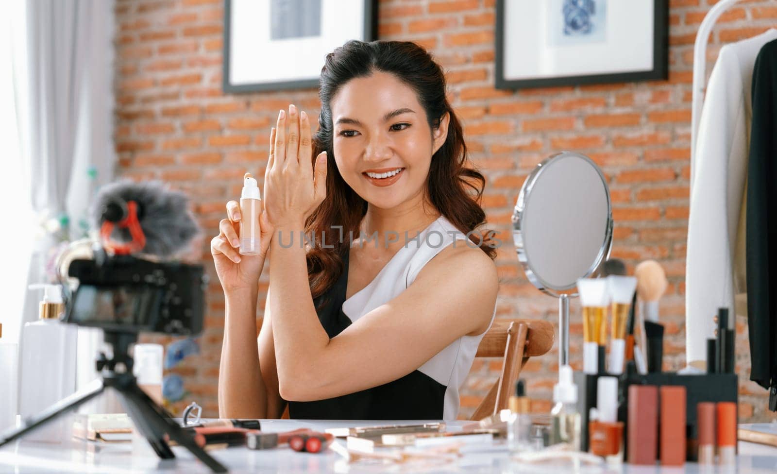 Woman influencer shoot live streaming vlog video review makeup uttermost social media or blog. Happy young girl with cosmetics studio lighting for marketing recording session broadcasting online.