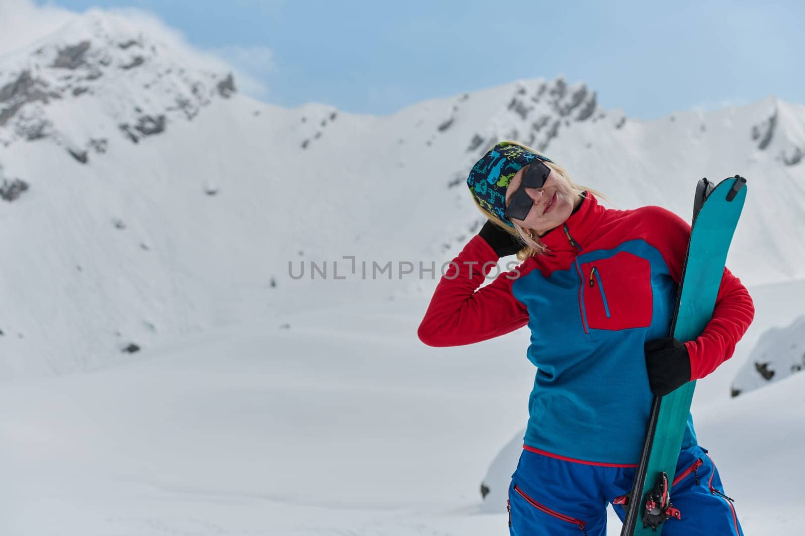 A professional woman skier rejoices after successfully climbing the snowy peaks of the Alps.
