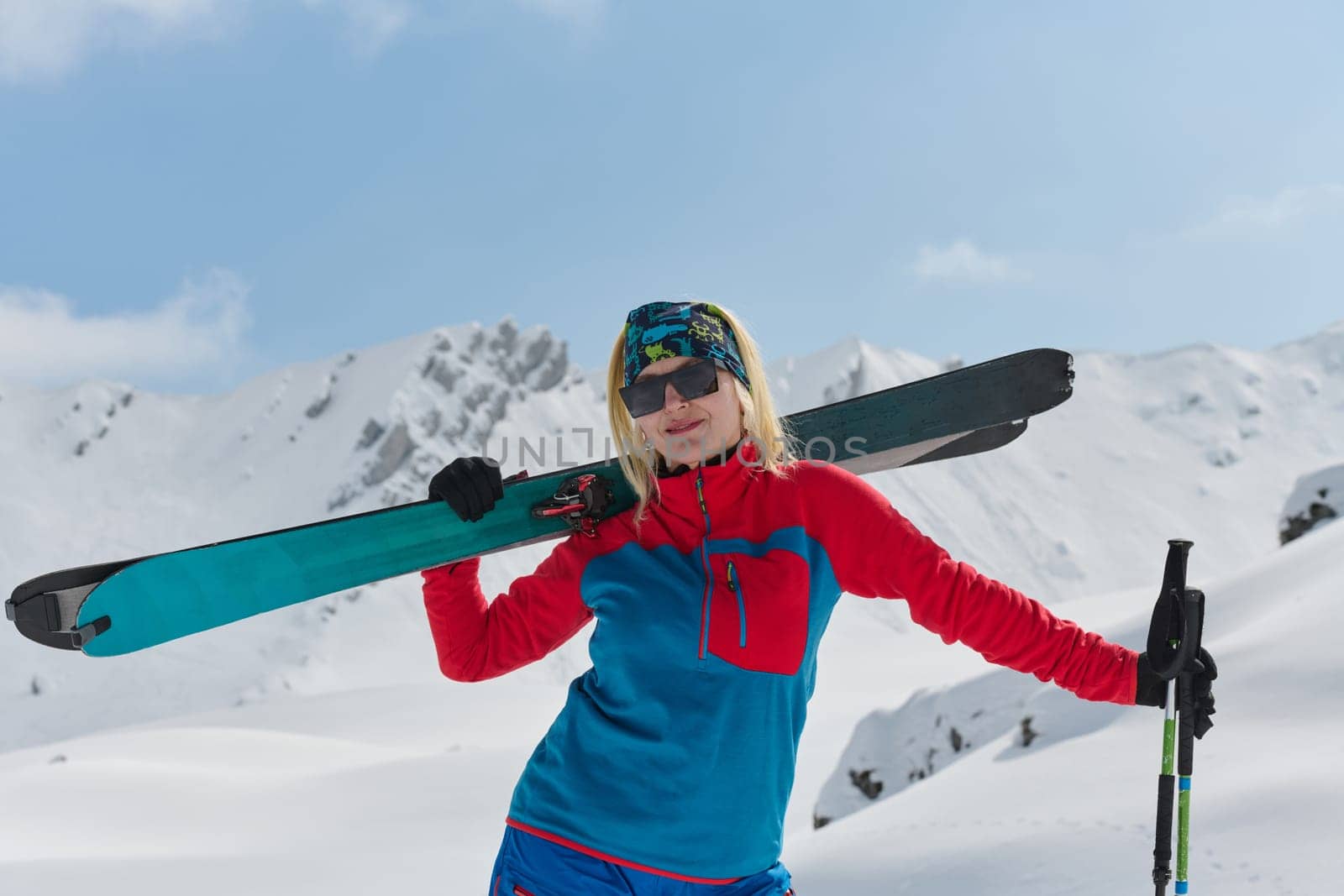 A professional woman skier rejoices after successfully climbing the snowy peaks of the Alps by dotshock