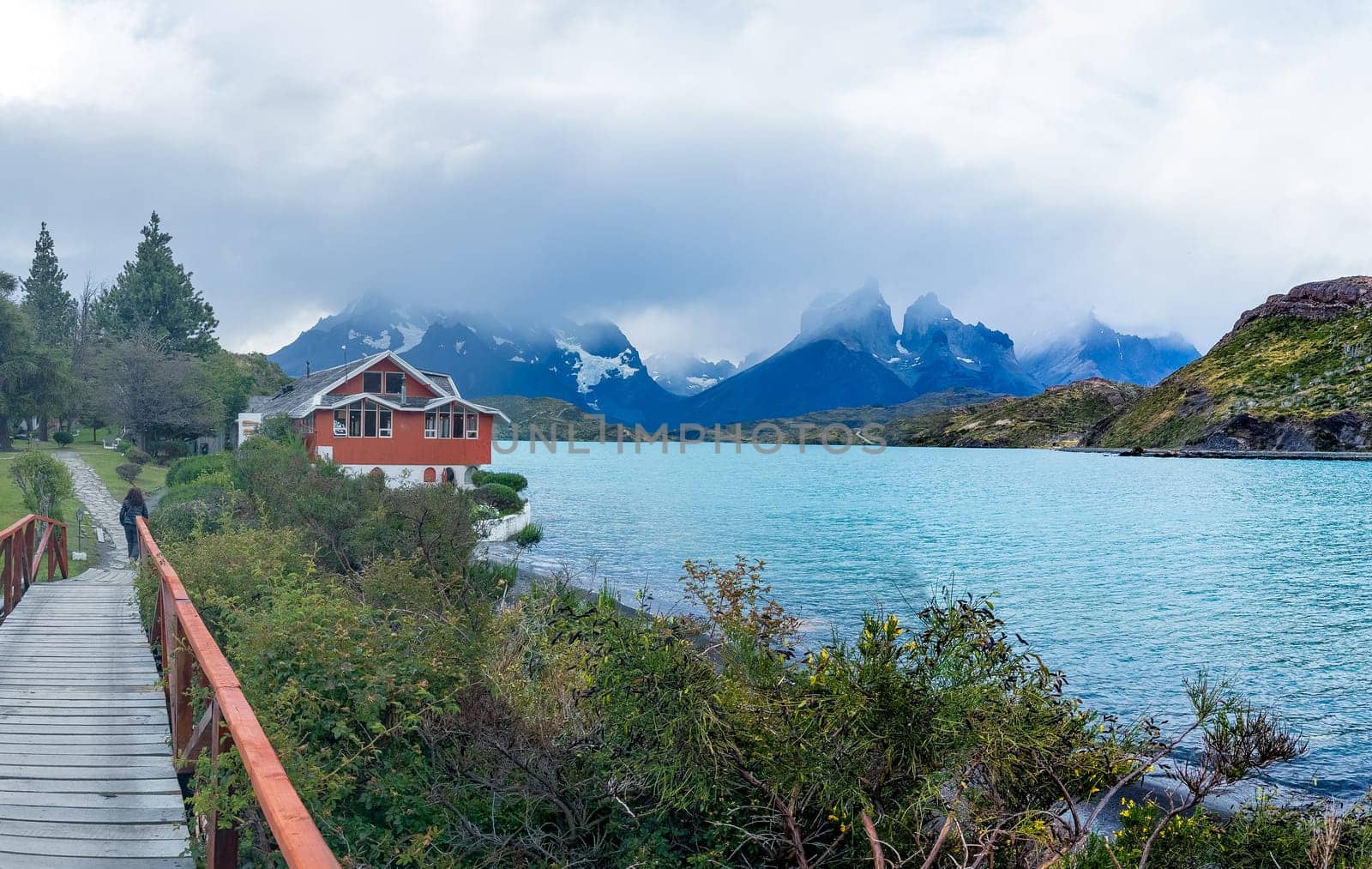 A striking red house by a turquoise lake with misty mountains.
