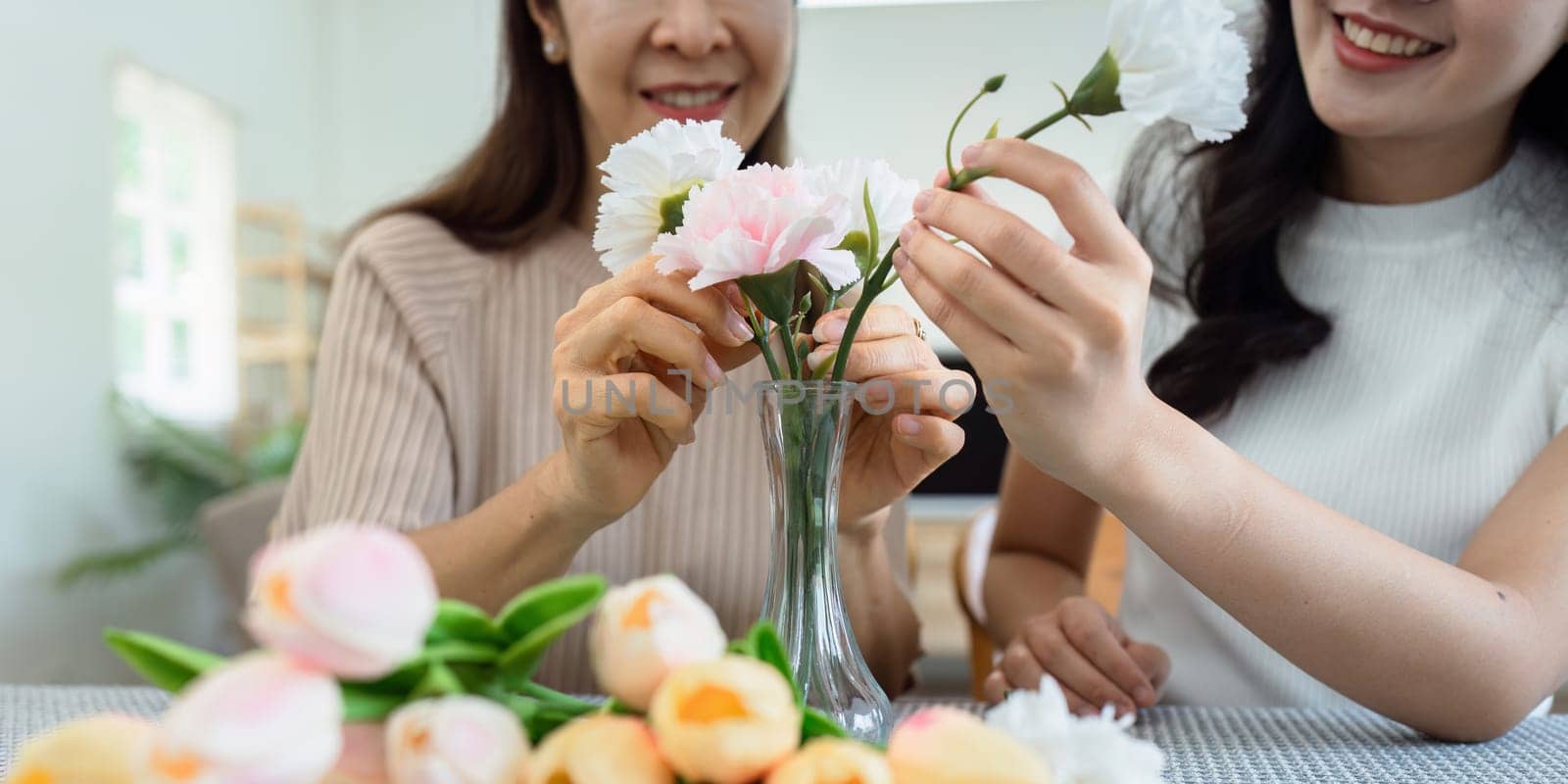 Mother and daughter arrange flower together at home on the weekend, family activities, mother and daughter do activities together on Mother's Day by itchaznong