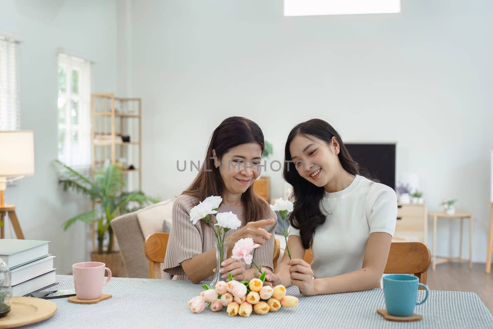 Mother and child arrange flowers together at home on the weekend, family activities, mother and daughter do activities together on Mother's Day.