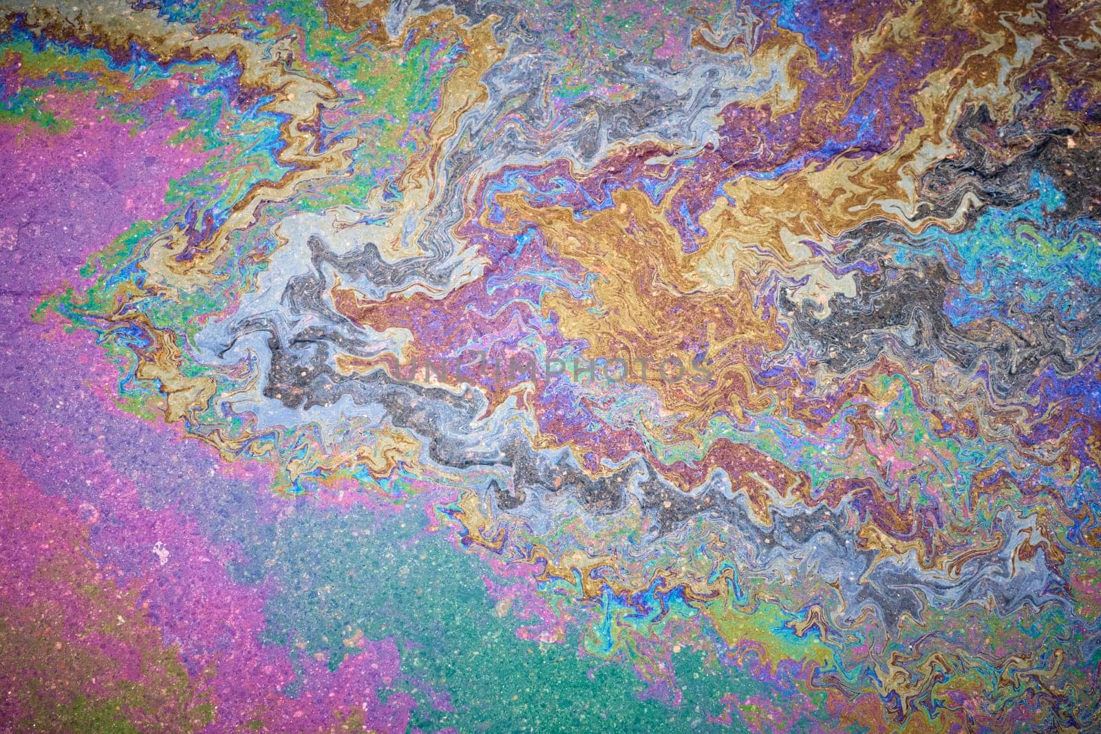 Marble spills on water from gasoline and oil stains. Abstract background from spilled motor oil, gas or gasoline on the asphalt.