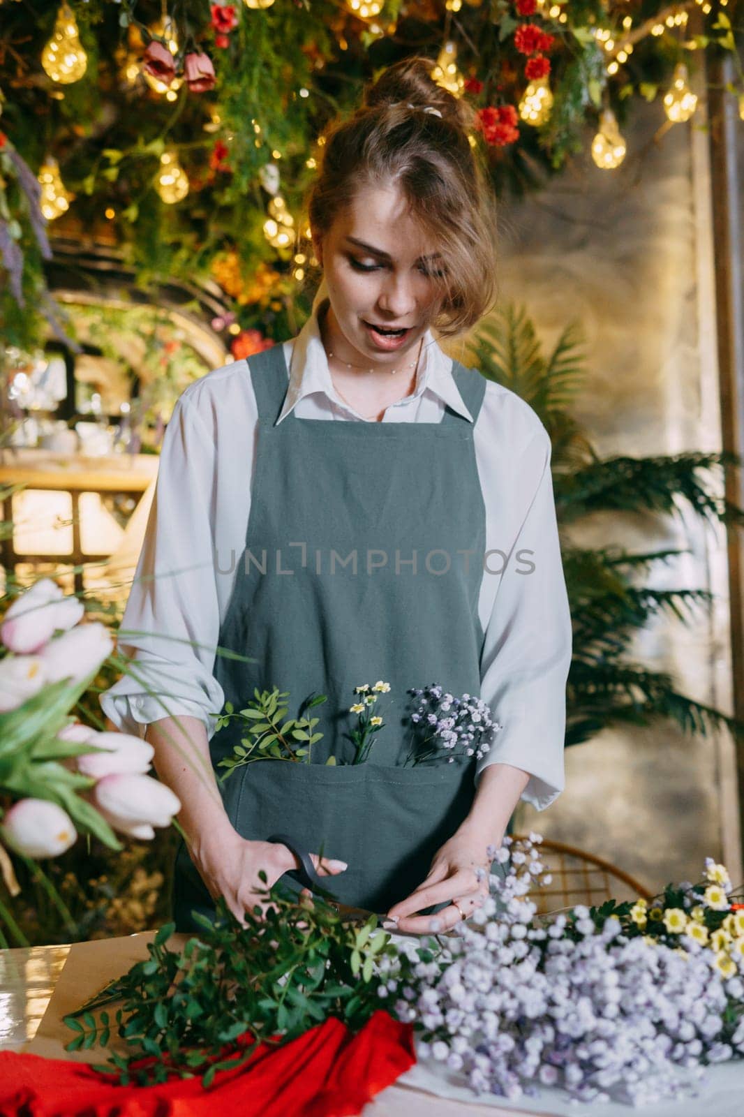 A woman in her florist shop collects bouquets of flowers. The concept of a small business. Bouquets of tulips for the holiday on March 8