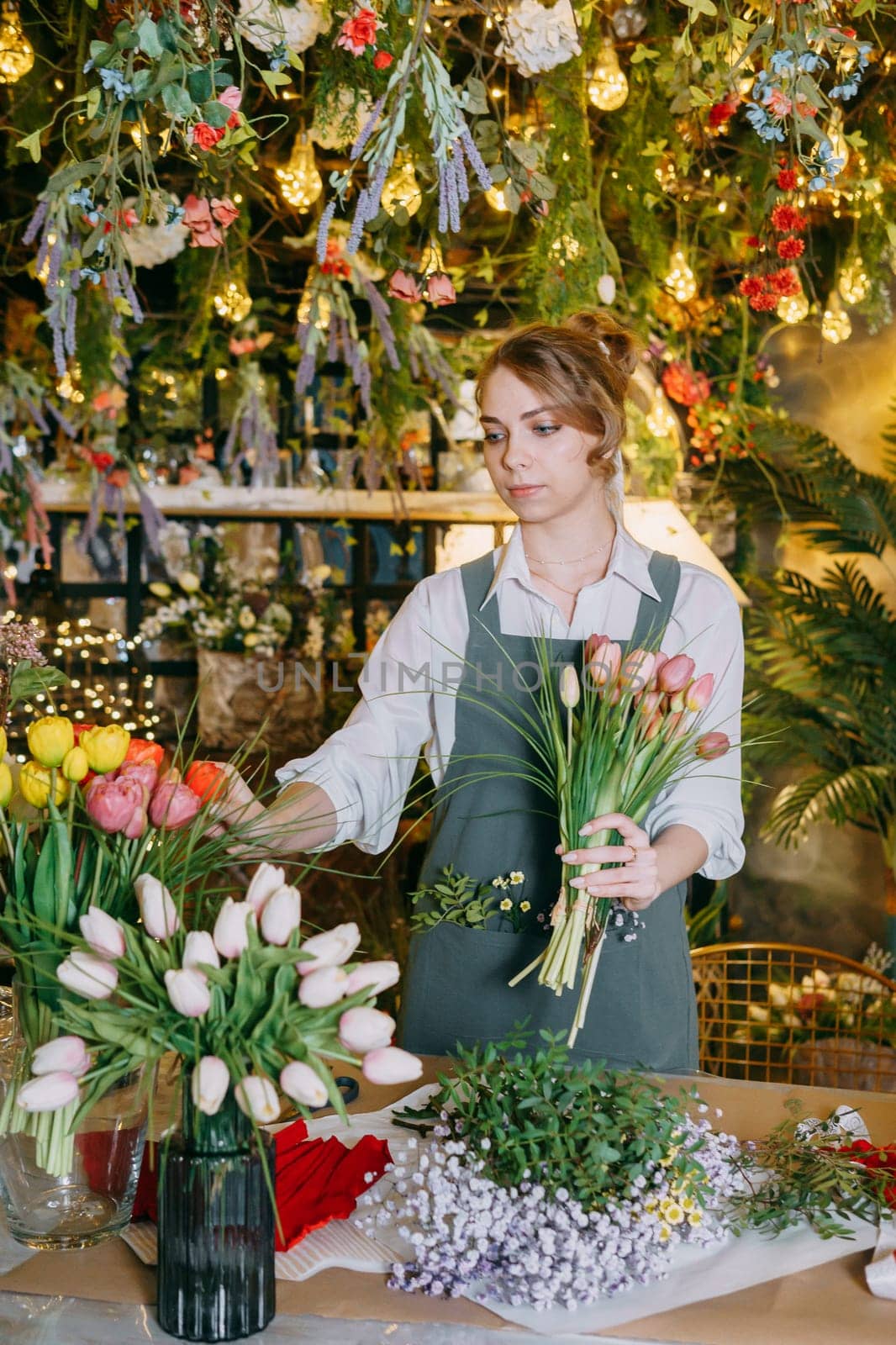 A woman in her florist shop collects bouquets of flowers. The concept of a small business. Bouquets of tulips for the holiday on March 8