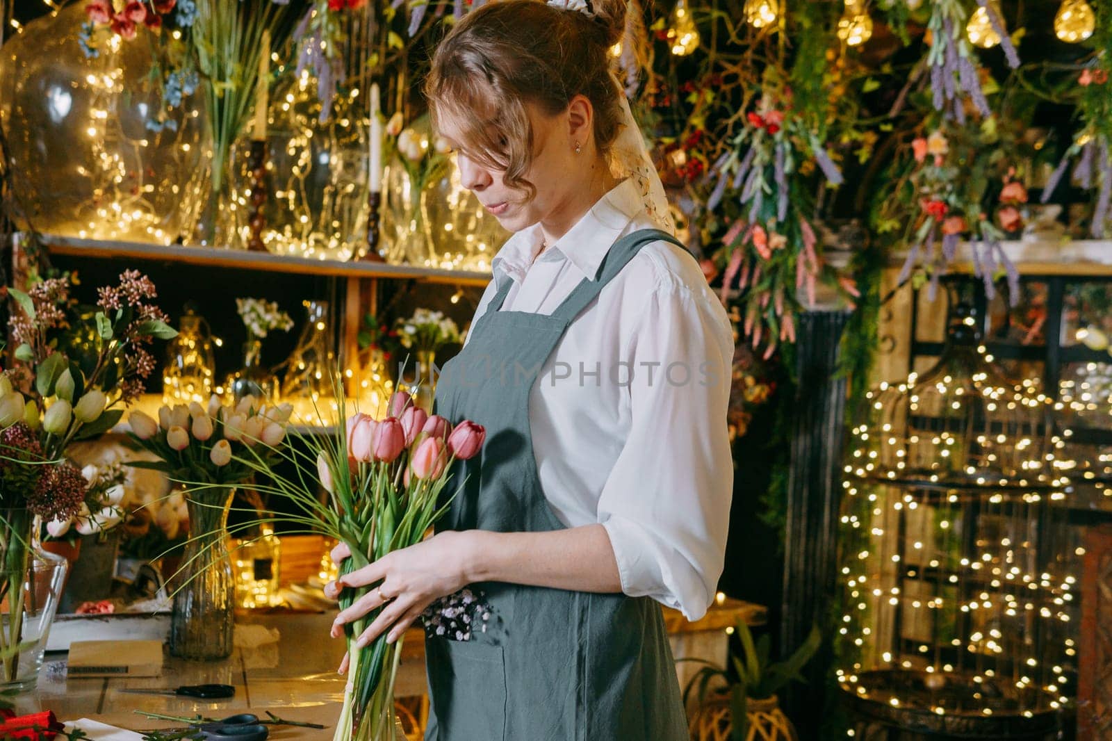 A woman in her florist shop collects bouquets of flowers. The concept of a small business. Bouquets of tulips for the holiday on March 8