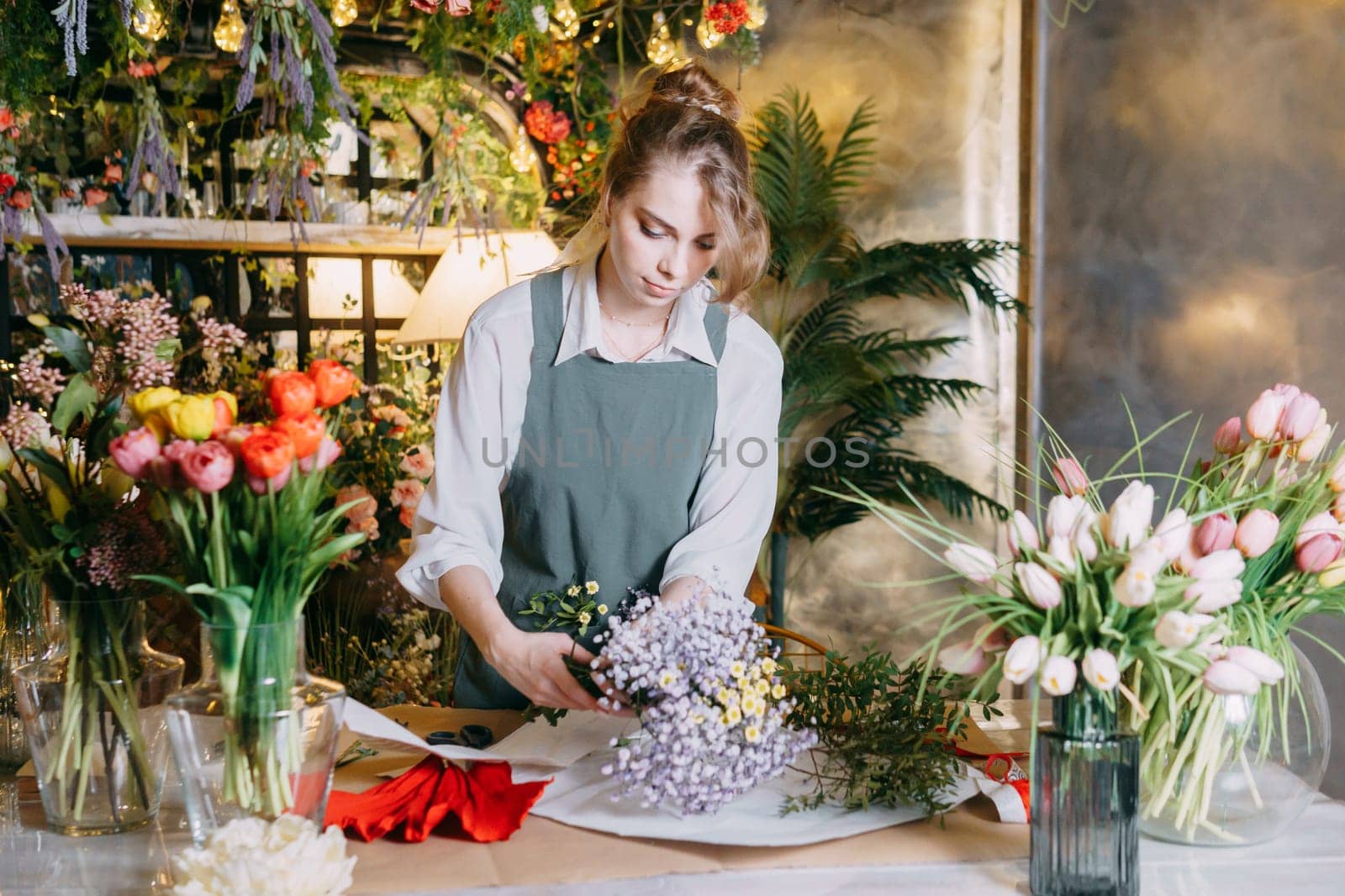 A woman in her florist shop collects bouquets of flowers. The concept of a small business. Bouquets of tulips for the holiday on March 8