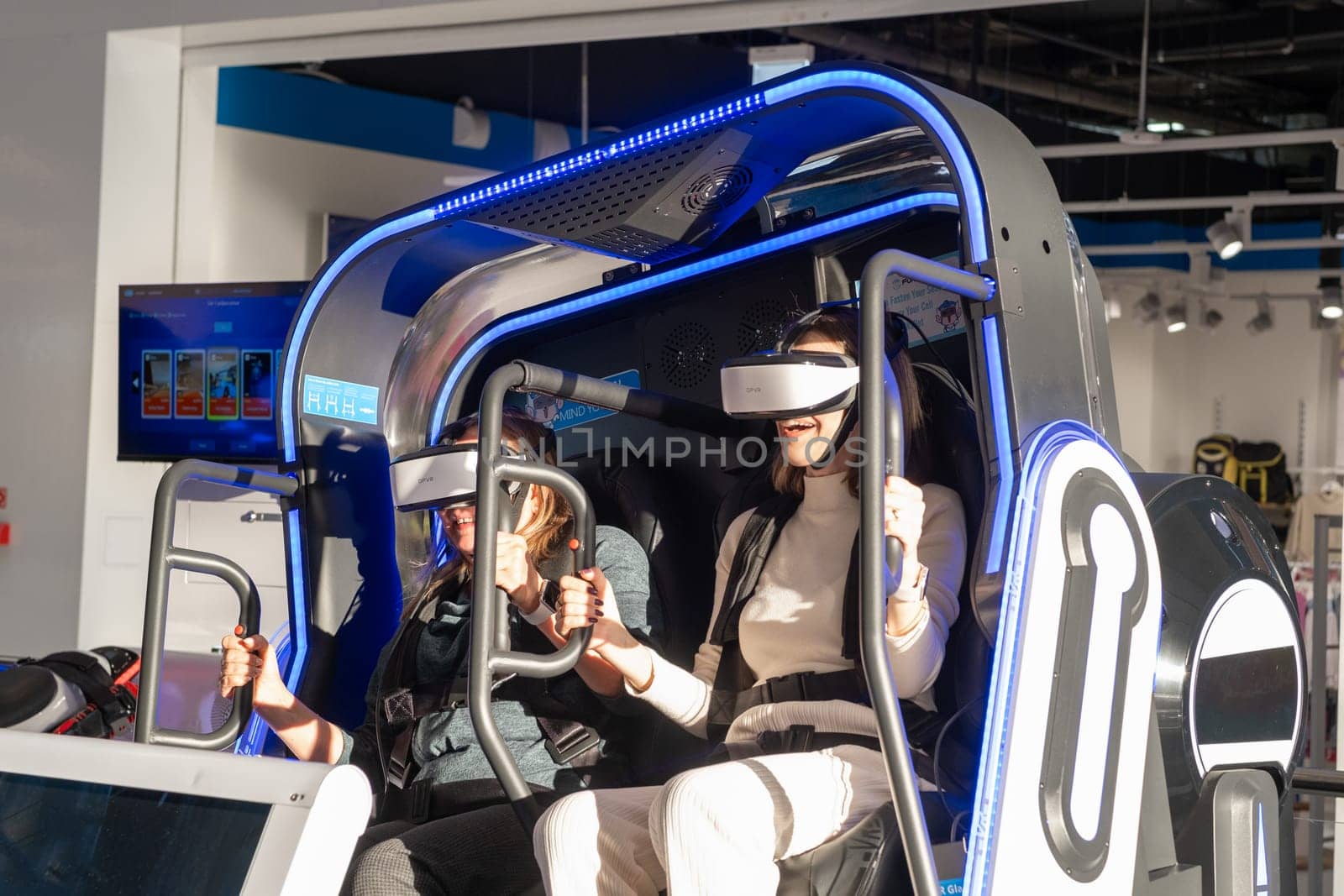 Two woman is sitting in an electric blue virtual reality chair by AnatoliiFoto