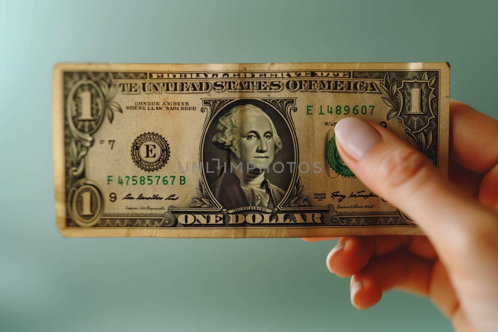 A person is holding a banknote in their hand, between their thumb and finger. The rectangular paper currency is one dollar cash, with intricate font design